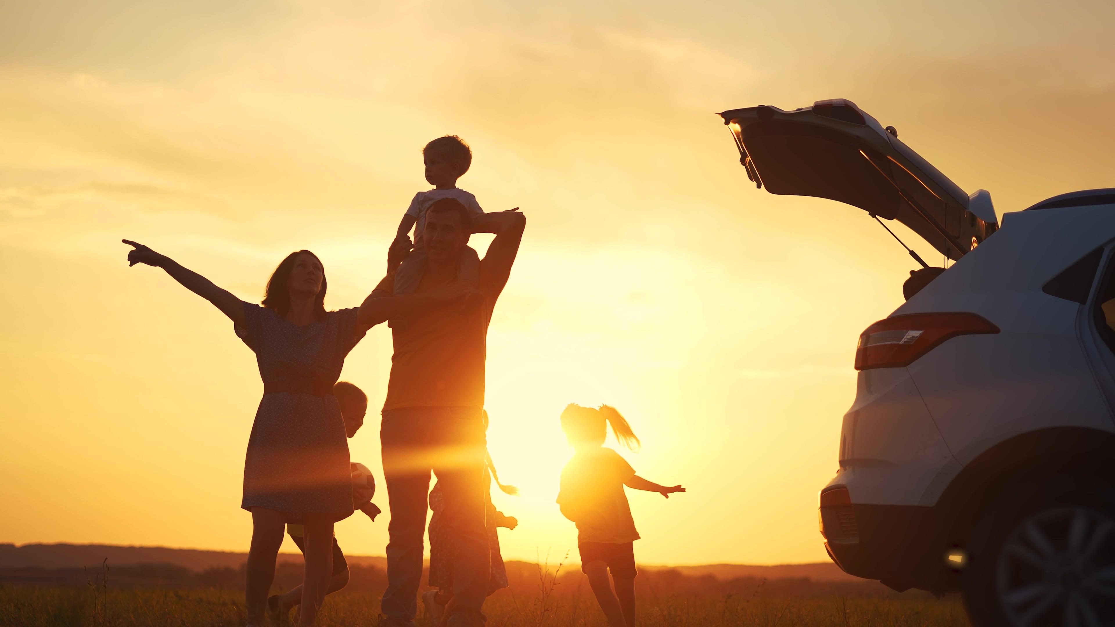 Eine Familie an einem Auto im Sonnenuntergang