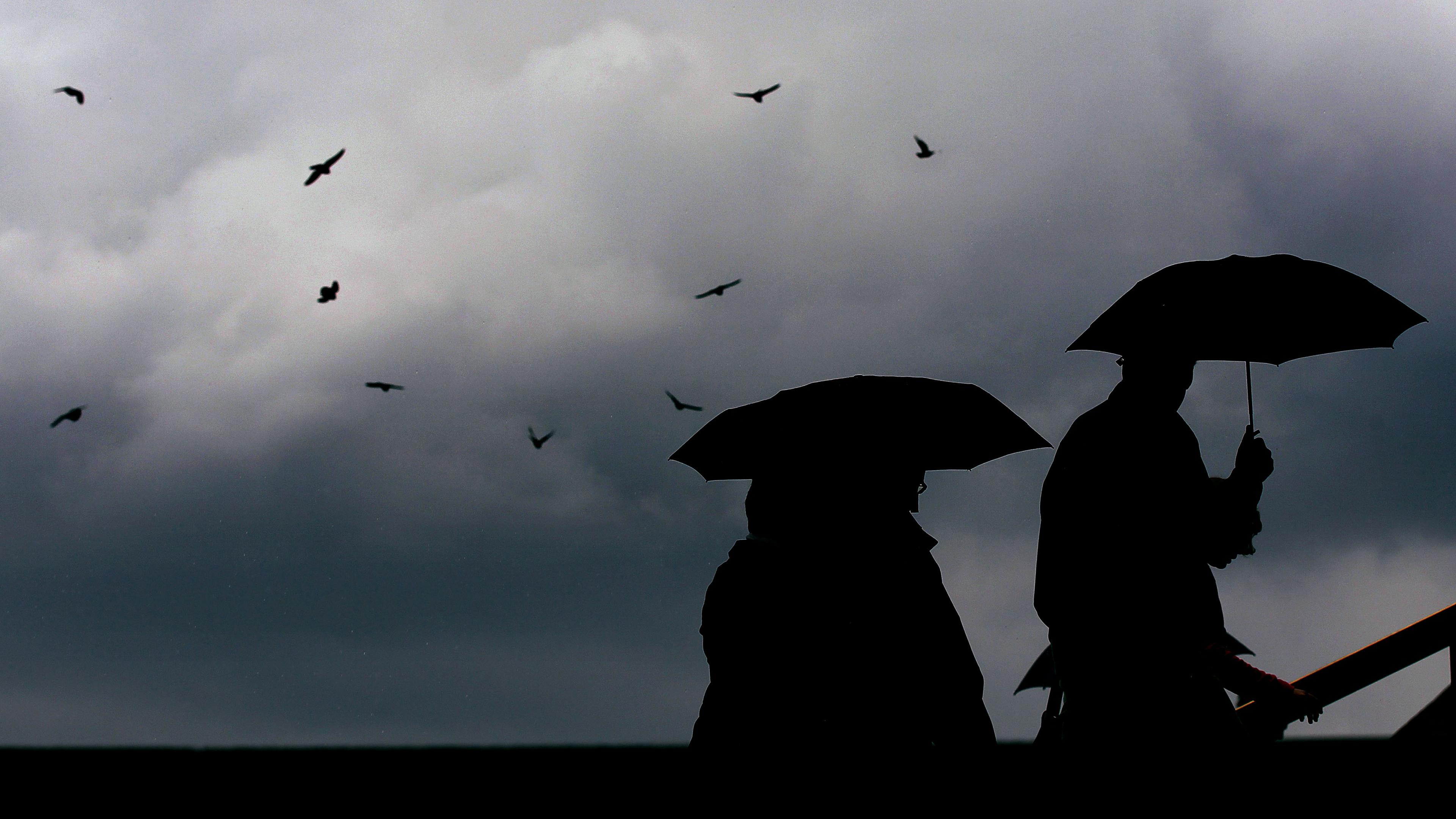 Nordrhein-Westfalen, Köln: Passanten gehen mit Regenschirmen durch eine Stadt. Archivbild