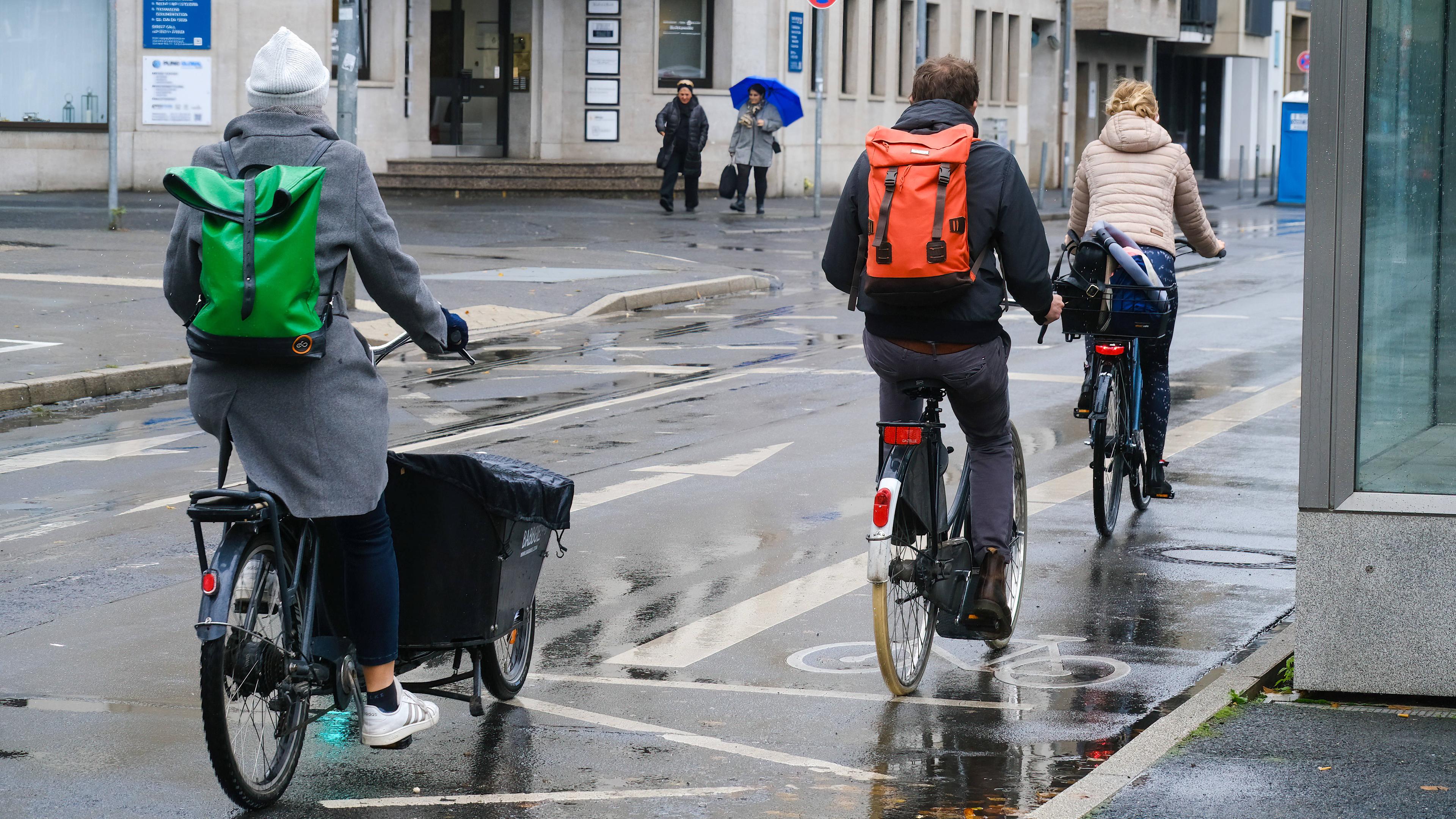 Drei Fahrradfahrer auf regennasser Straße