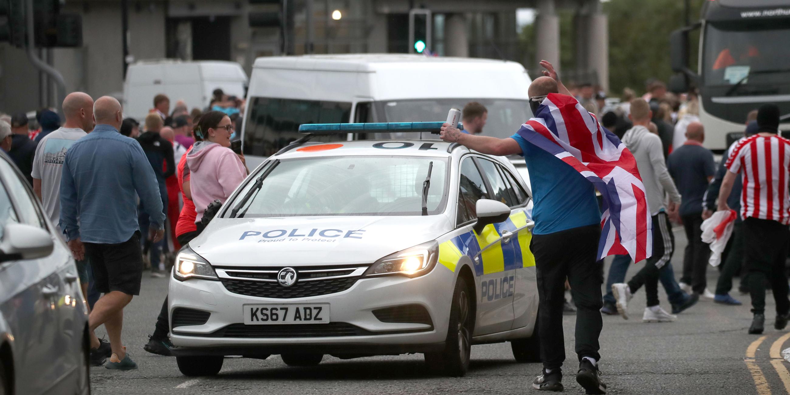 Menschen protestieren im Stadtzentrum von Sunderland, in der Mitte steht ein Polizeiauto.