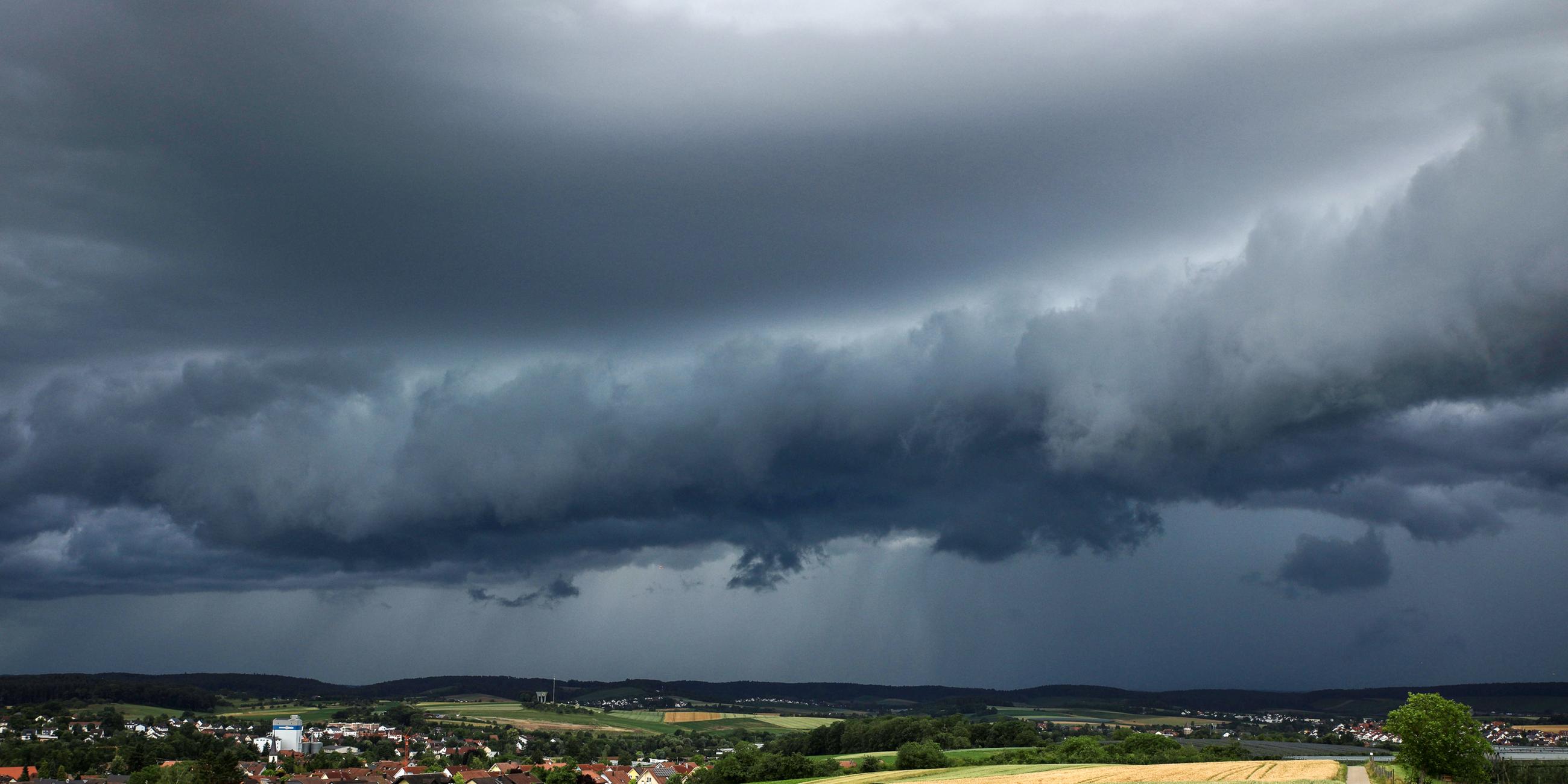 Baden-Württemberg, Heilbronn: Eine Gewitterzelle mit dunklen Wolken baut sich am Himmel und hinter Feldern nahe Heilbronn auf.