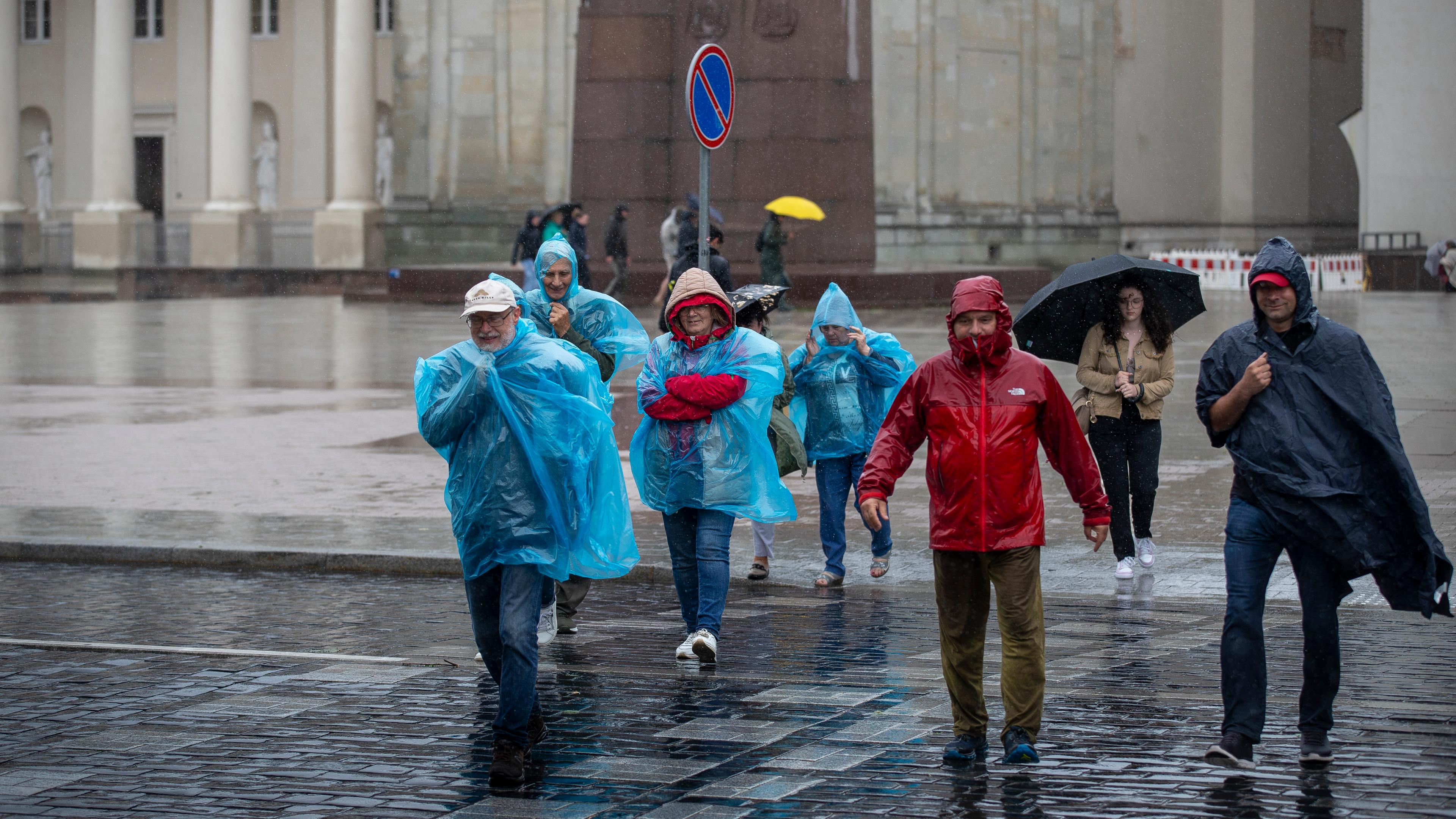 Menschen überqueren an einem regnerischen Tag eine Straße in Vilnius, Litauen, Montag, 29. Juli 2024.