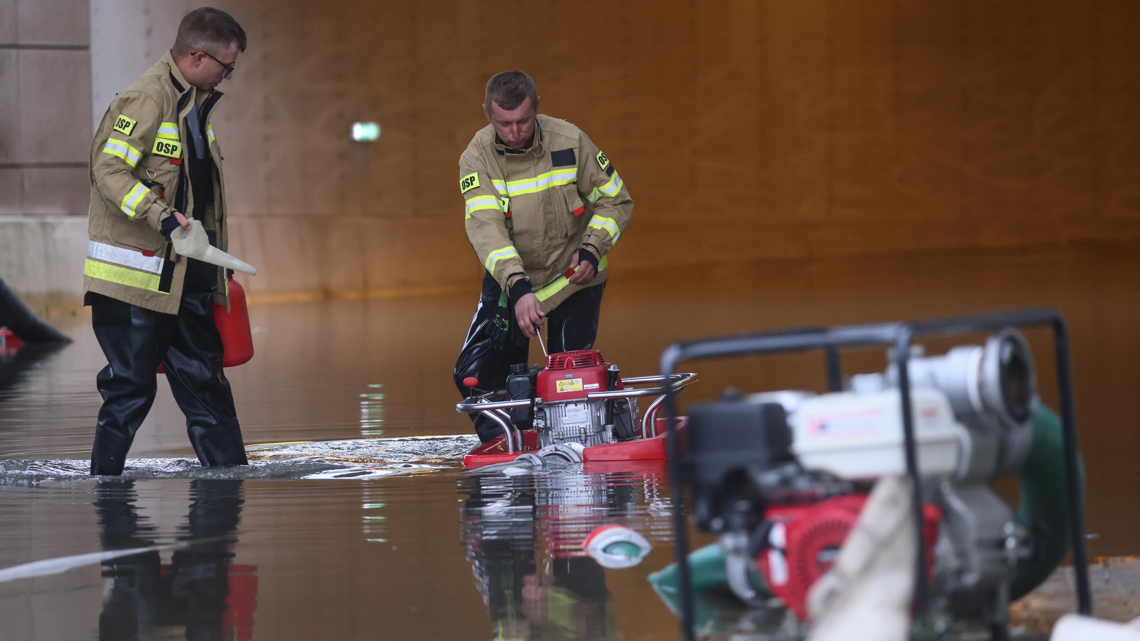 Zwei Feuerwehrmänner arbeiten im Hochwasser eines überfluteten Tunnel in der Nähe des Flughafens Fryderyk Chopin.