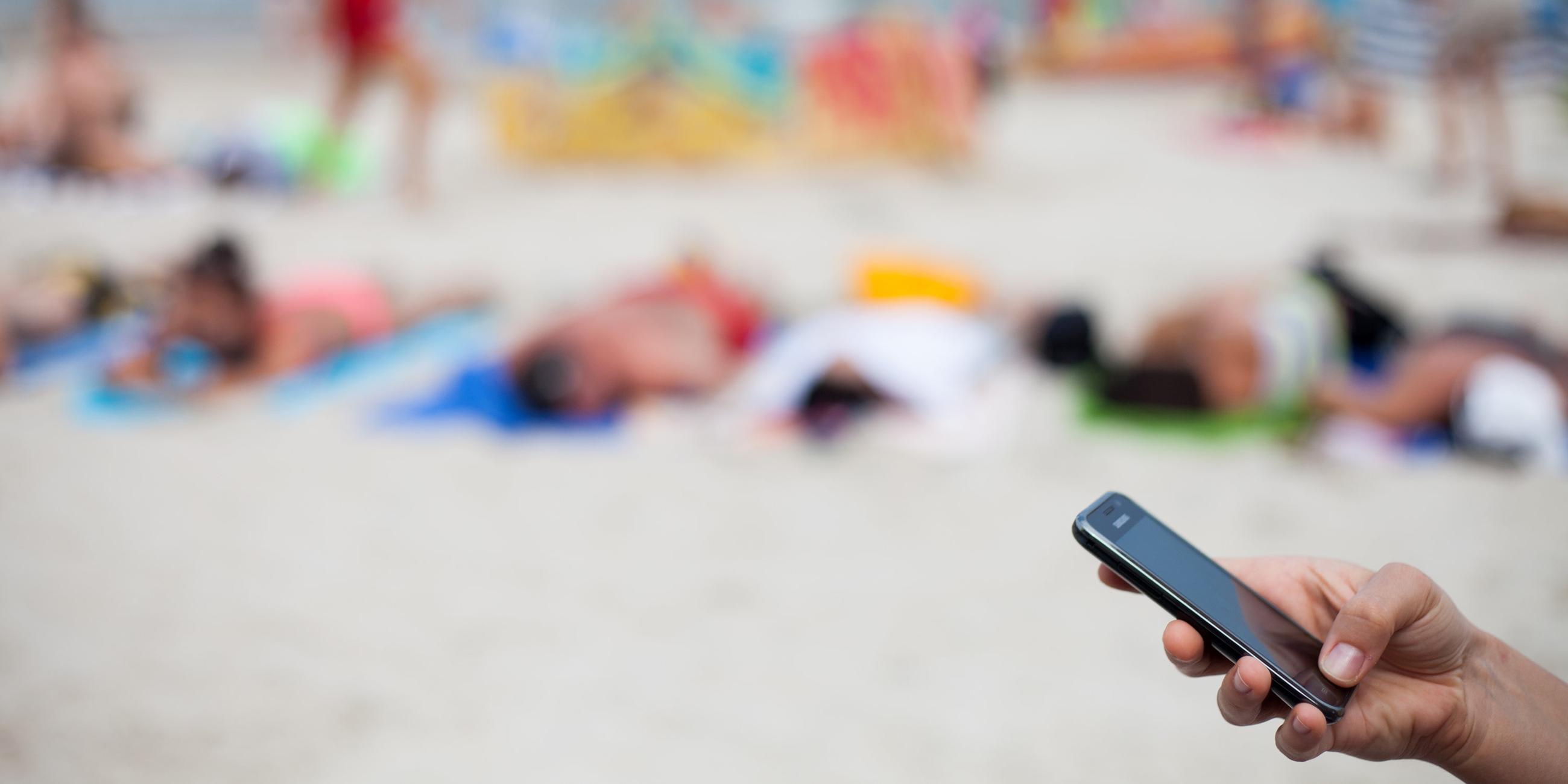 Polen, Kolben: Eine frau hält ein Mobiltelefon am Strand, Archivbild