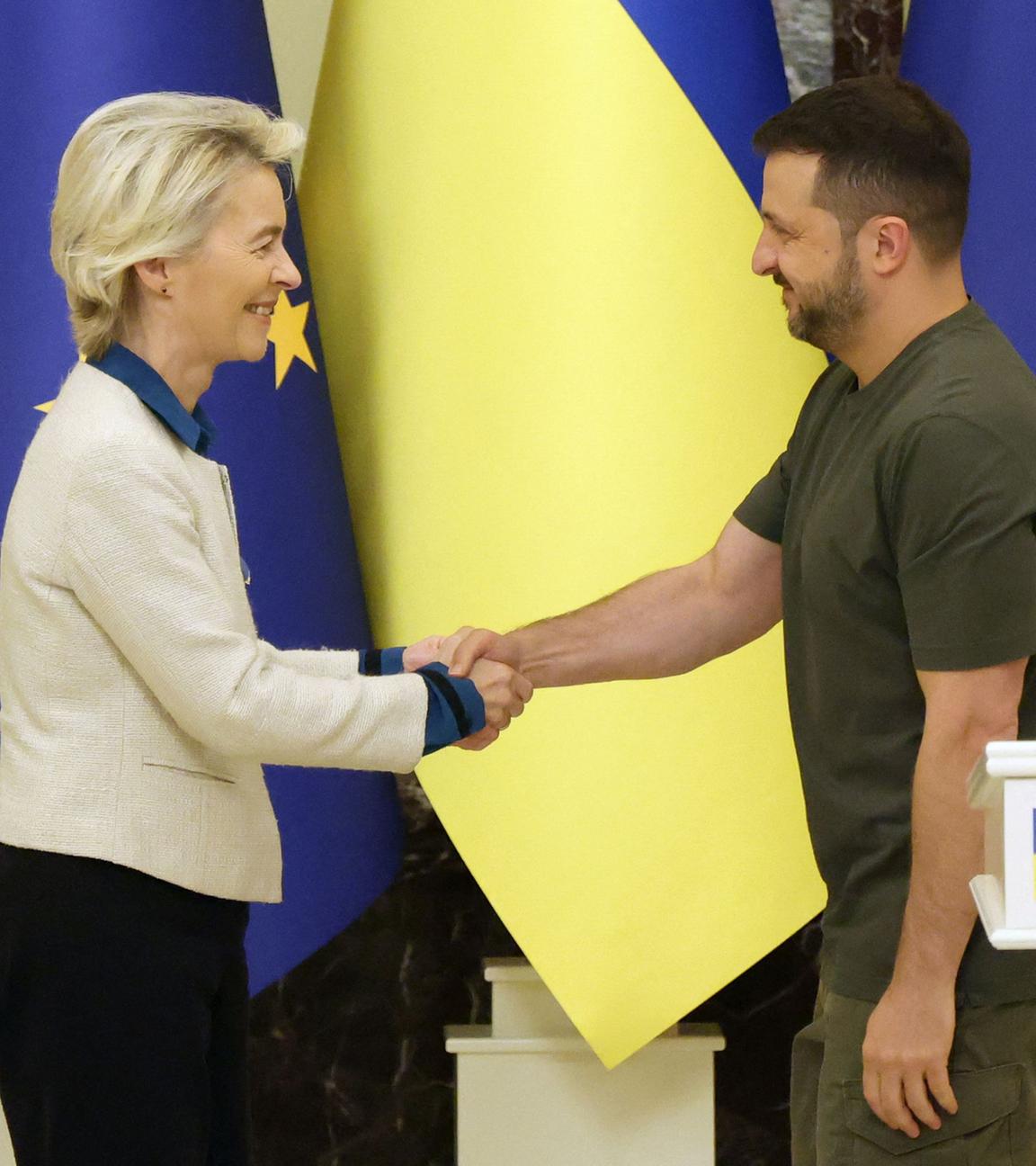 European Commission President Ursula von der Leyen (L) and Ukrainian President Volodymyr Zelensky shake hands after a joint