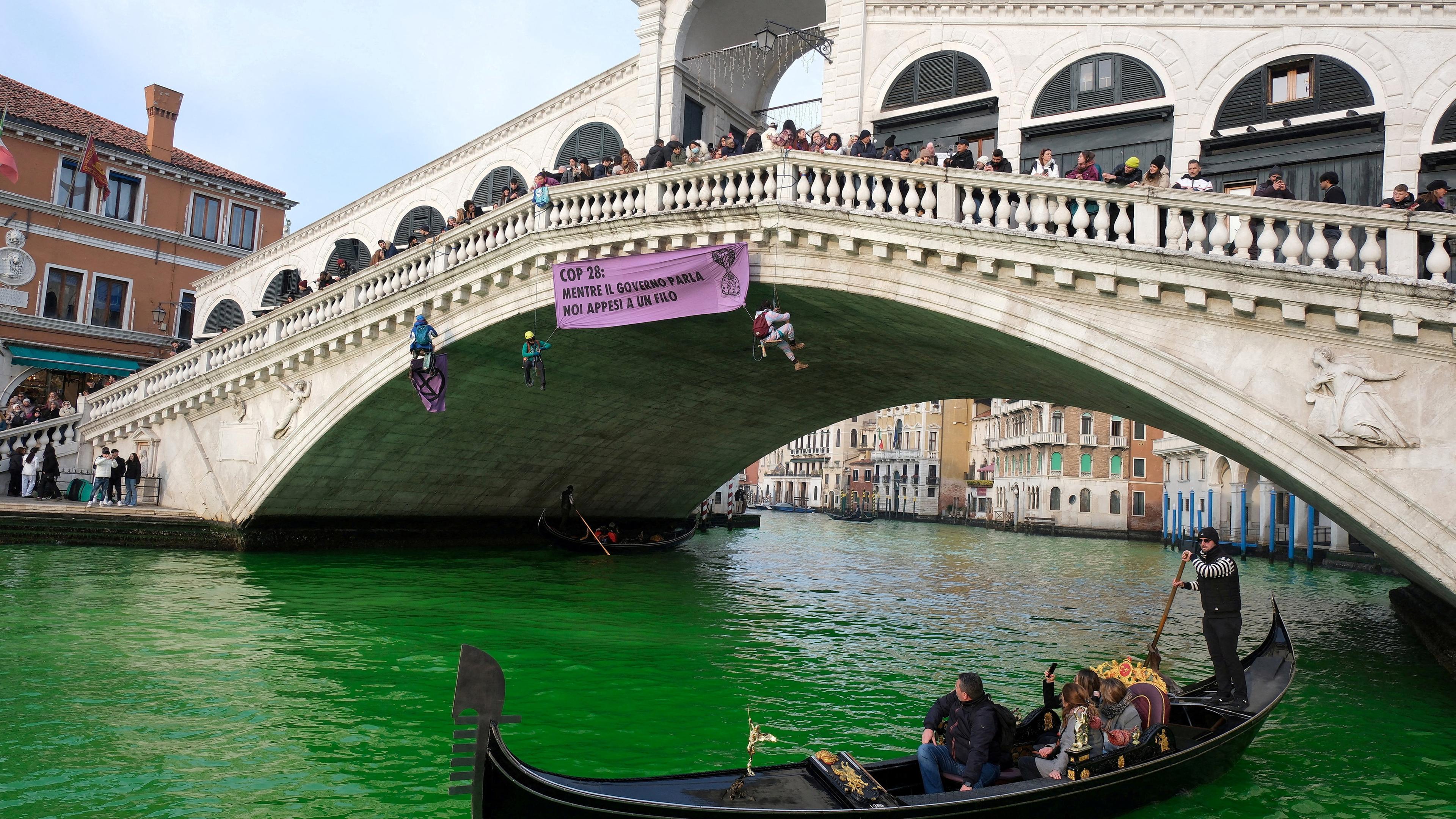 Eine Brücke über den Canal Grande in Venedig mit grünem Wasser. 