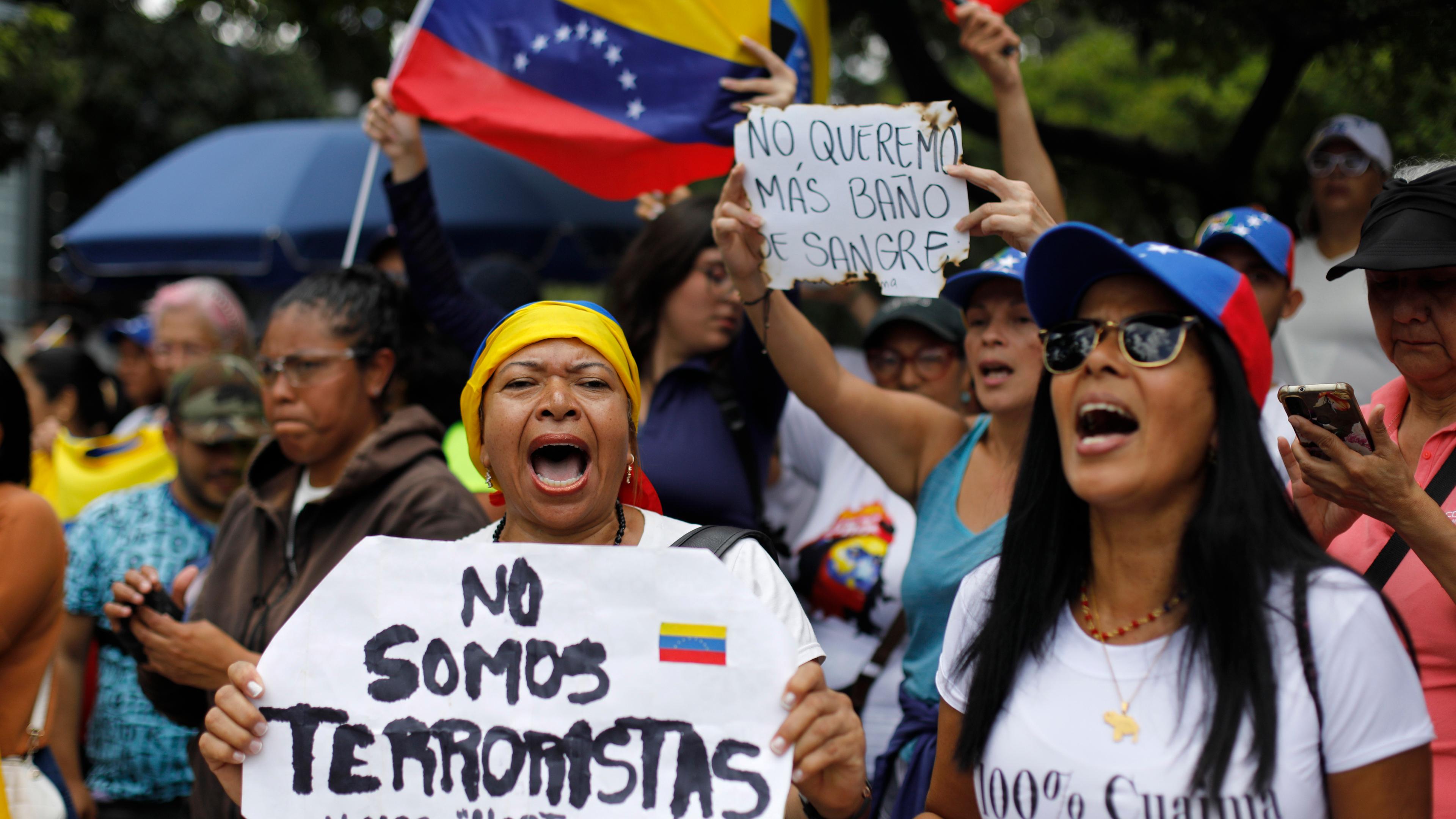 03.08.2024, Venezuela, Caracas: Eine Frau hält ein Schild mit der spanischen Aufschrift «Wir sind keine Terroristen», während sie mit anderen Anhängern auf die Ankunft der Oppositionsführerin Maria Corina Machado wartet.