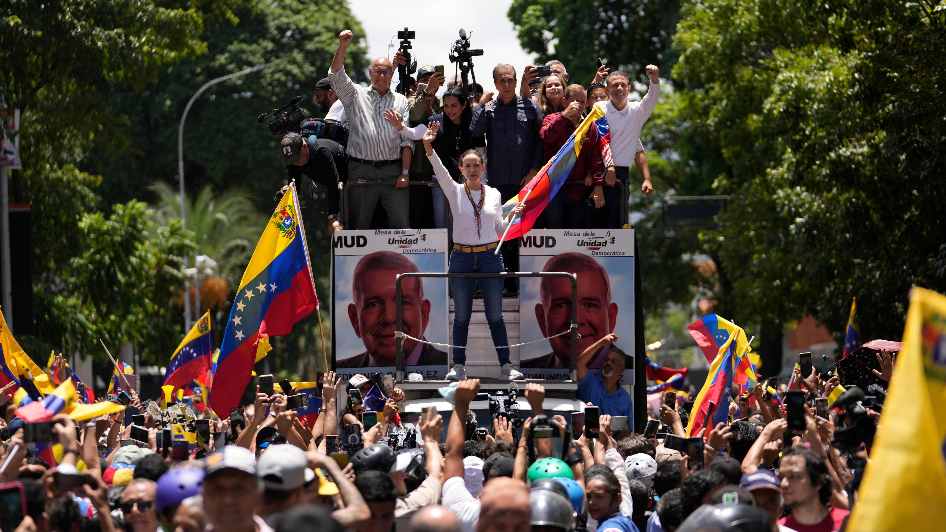 Opposition leader Maria Corina Machado holds a national flag while waving to supporters as she arrives for a rally in Caracas, Venezuela, Saturday, Aug. 3, 2024. 