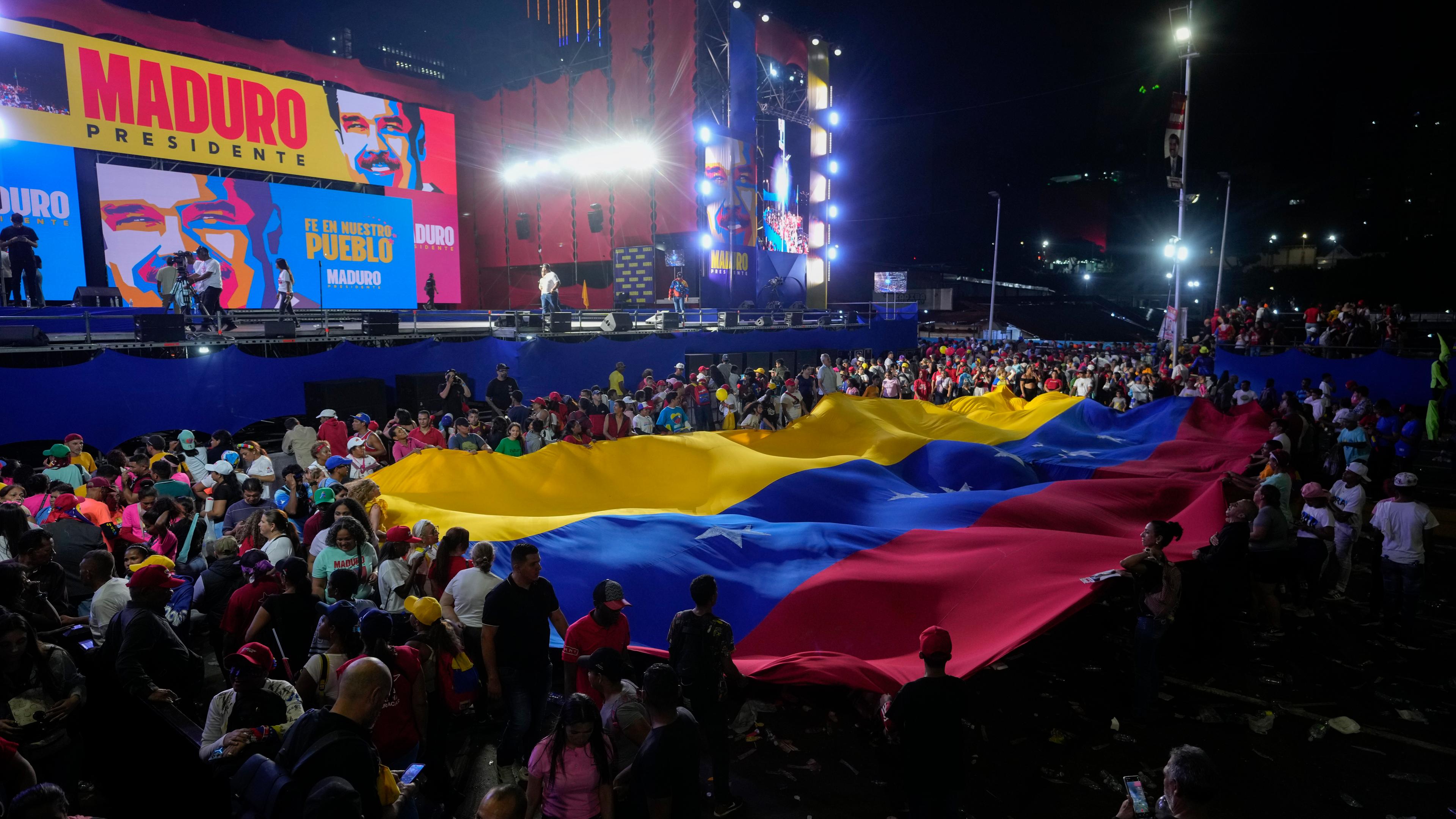 25.07.2024: Anhänger von Präsident Nicolas Maduro halten eine venezolanische Flagge während seiner Wahlkampfabschlusskundgebung in Caracas, Venezuela.