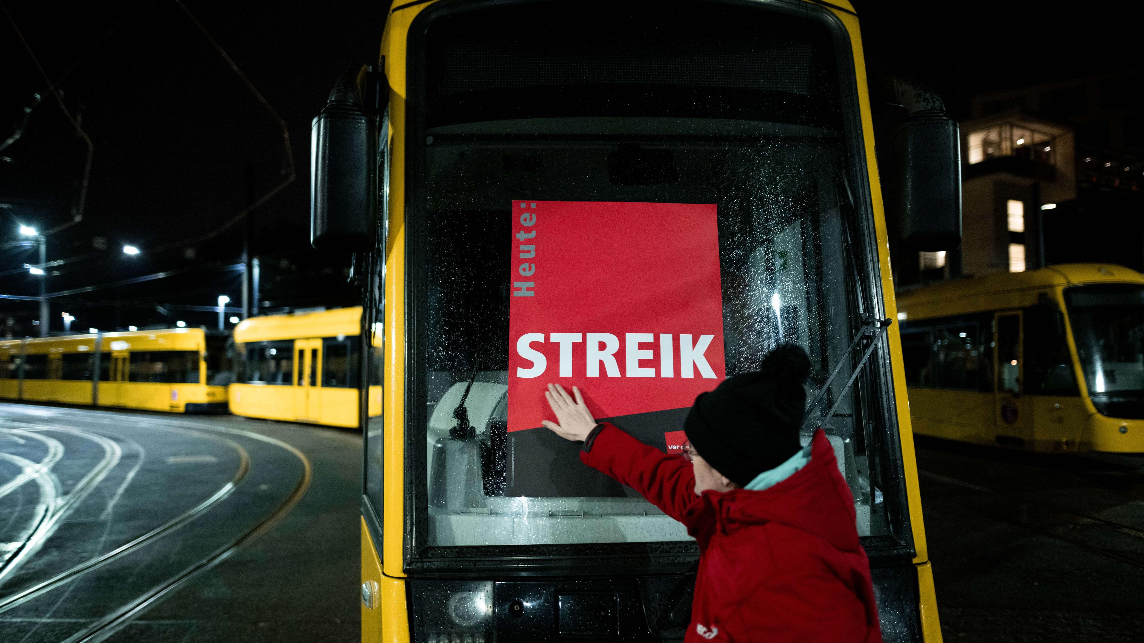 Eine Mitarbeiterin klebt ein Poster, auf dem «STREIK» steht, auf eine Bahn im Depot der Ruhrbahn in Essen.