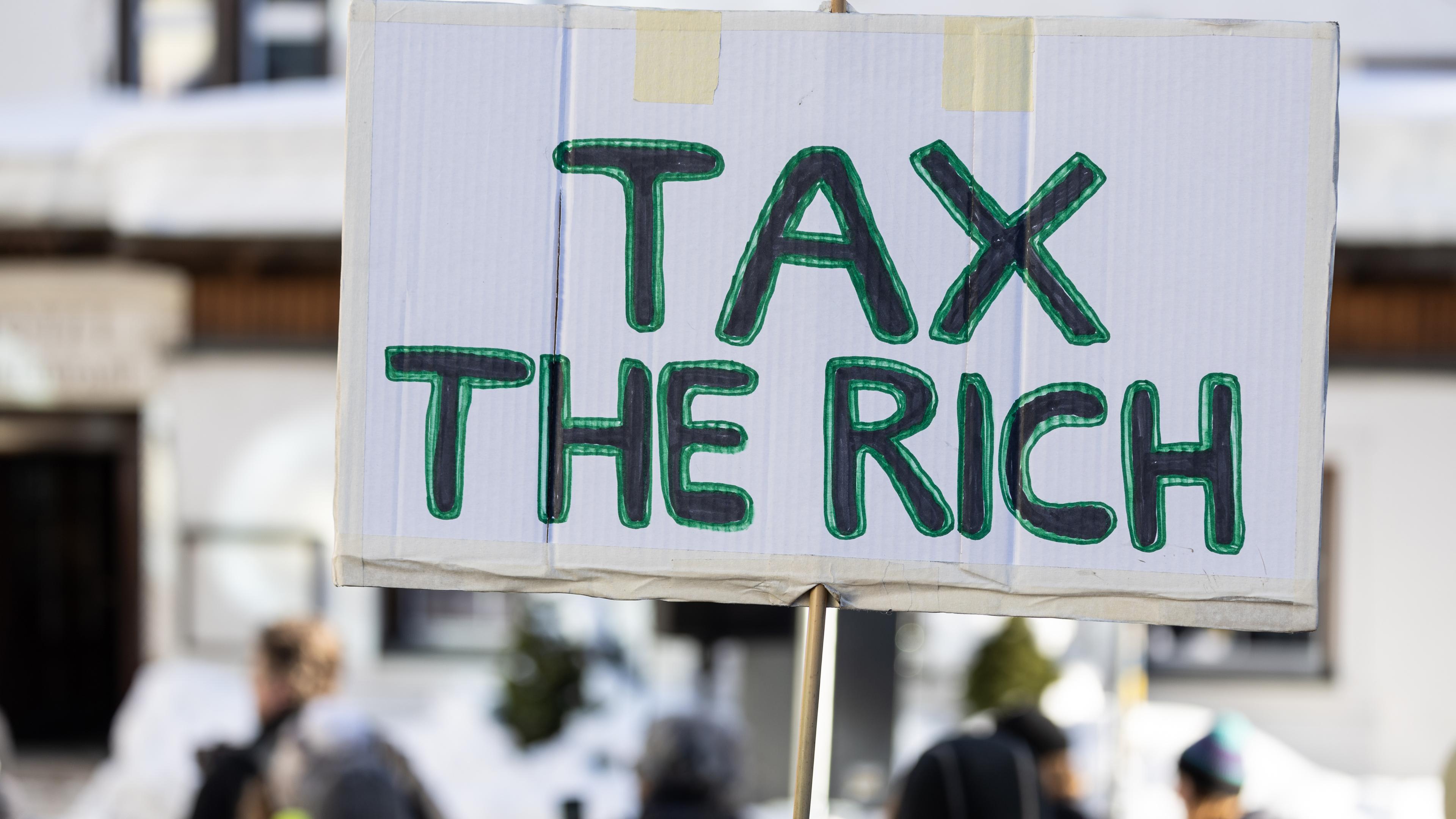 Auf einem Schild steht "Tax the rich".