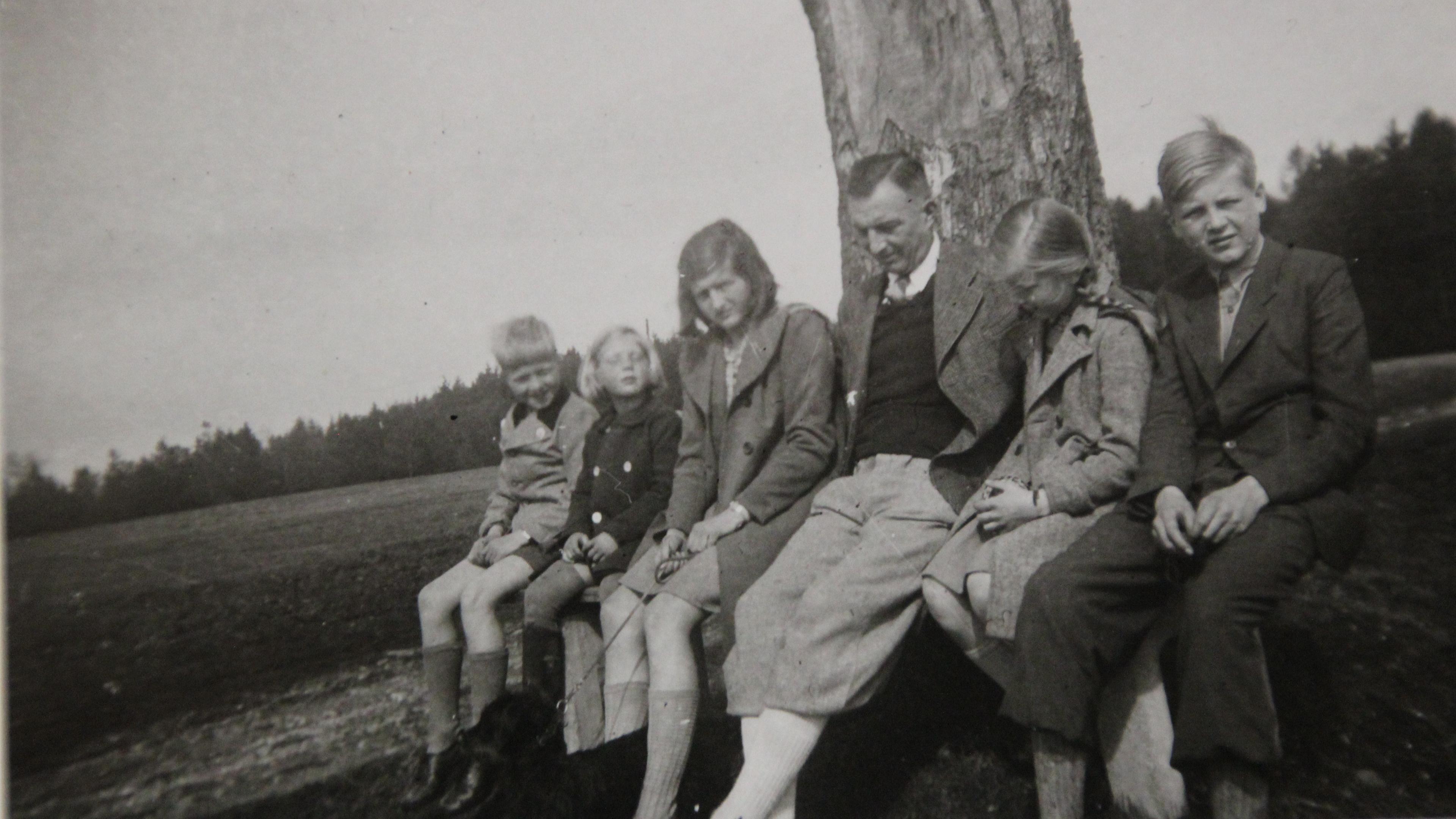  Schwarz-Weiß-Foto: Caesar von Hofacker sitzt mit seinen fünf Kindern vor einem Baum.