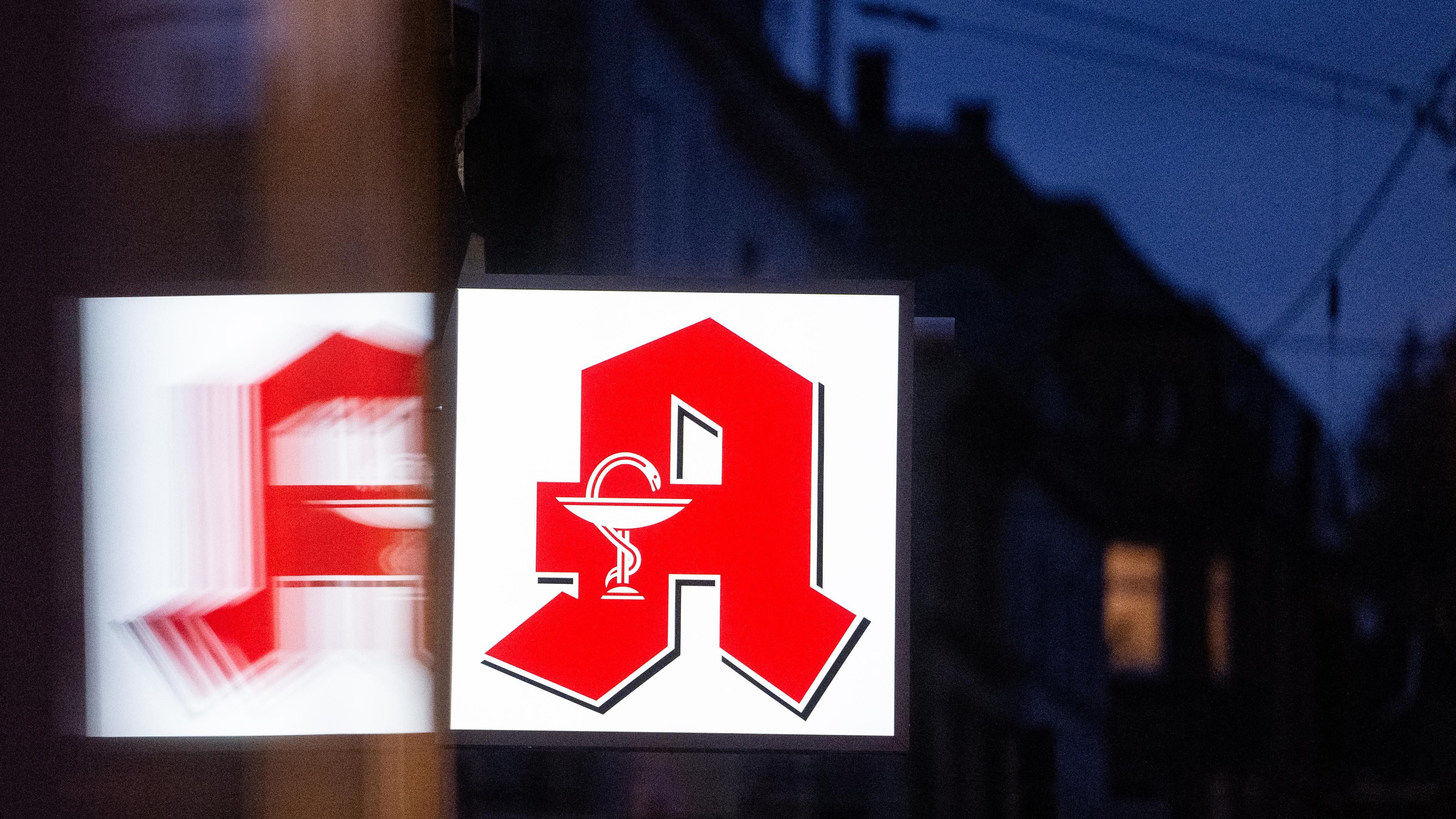 ARCHIV - 22.11.2023, Stuttgart: Ein Apothekenschild leuchtet an der Fassade eines Gebäudes in der Innenstadt.
