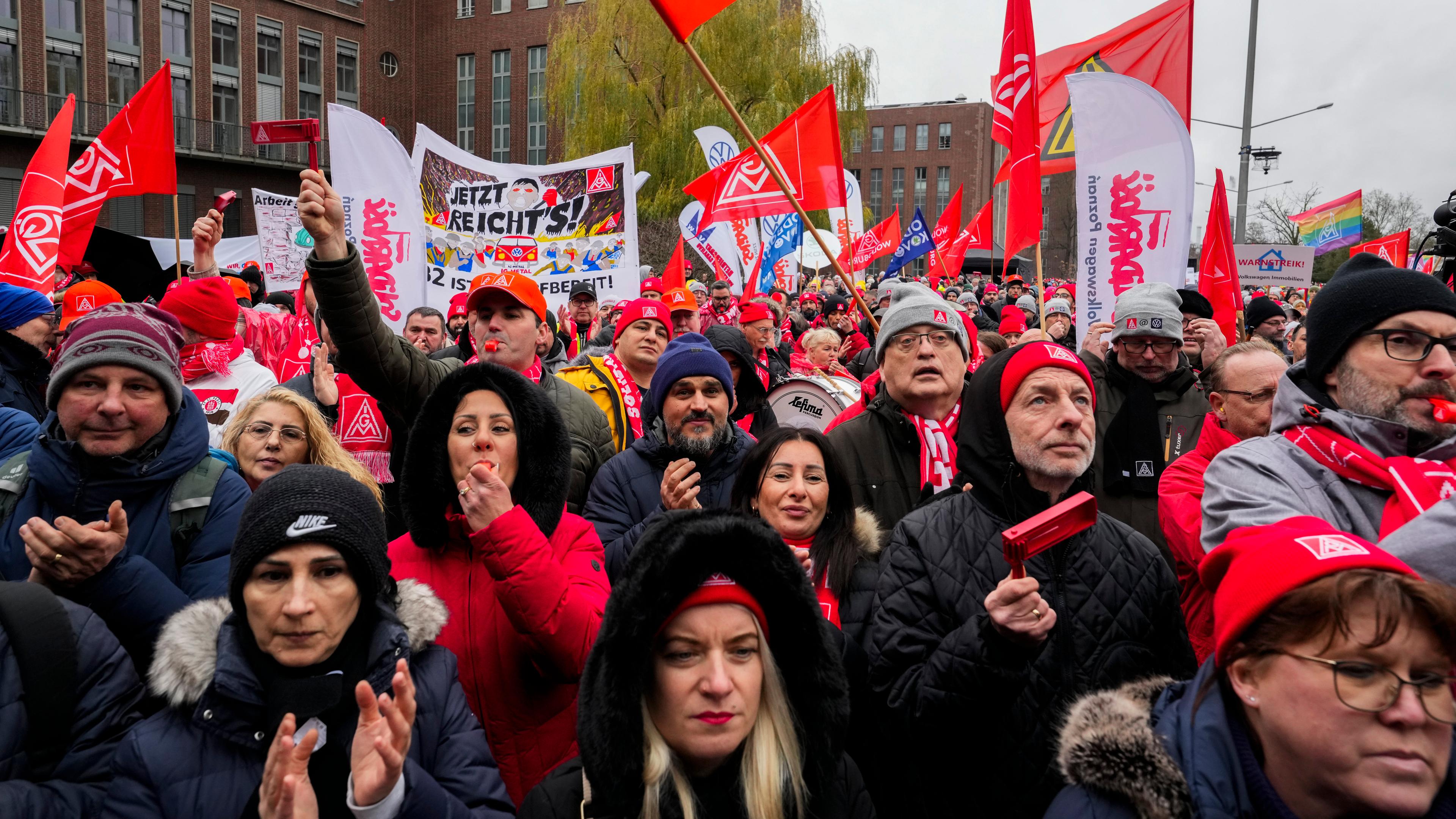 Teilnehmer am Warnstreik der IG Metall klatschen vor dem Hauptsitz des Autobauers Volkswagen in Wolfsburg.