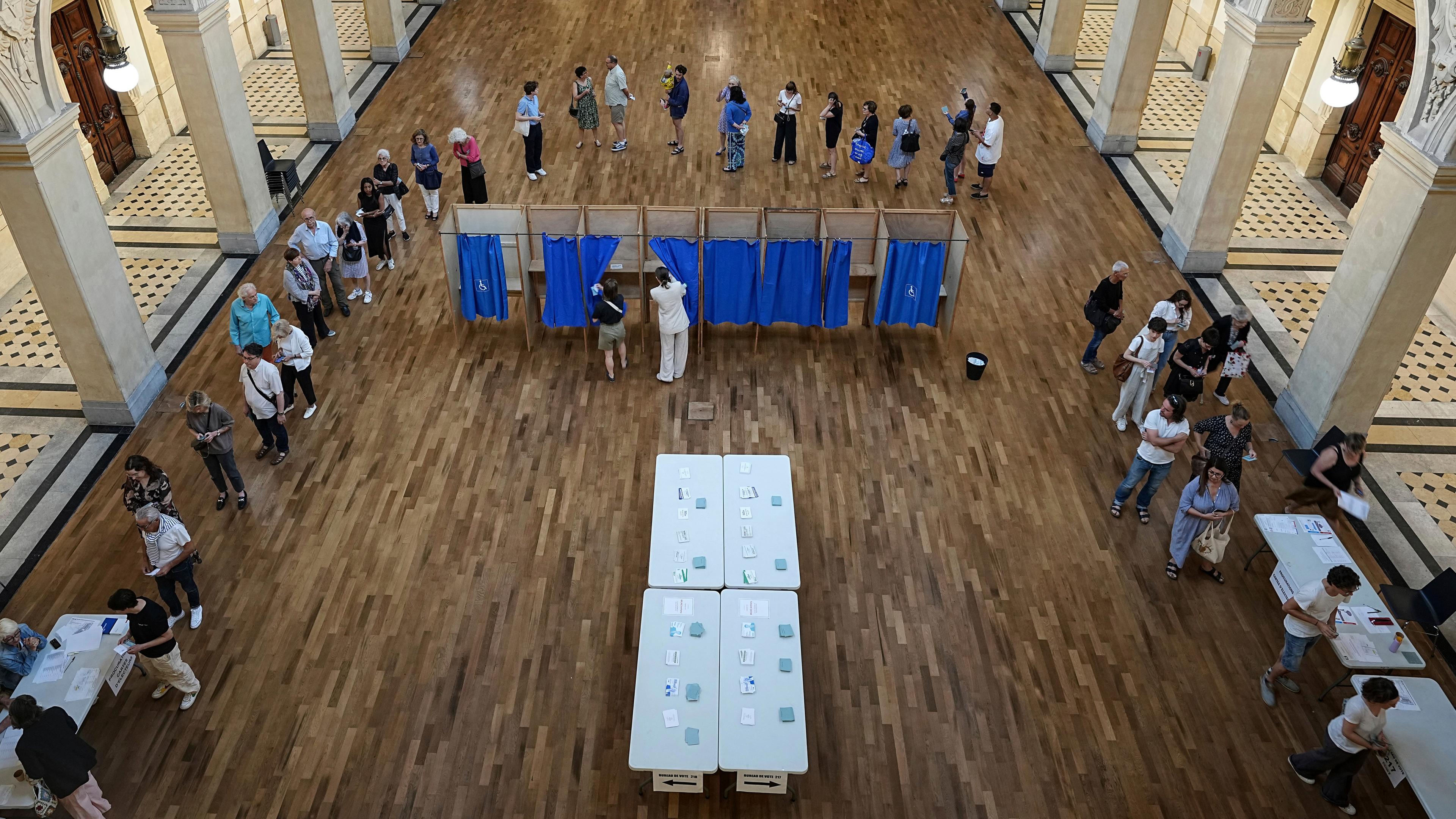Wähler warten an einem Wahllokal, um ihre Stimme in der ersten Runde der französischen Parlamentswahlen abzugeben, in Lyon, 30.06.2024. 