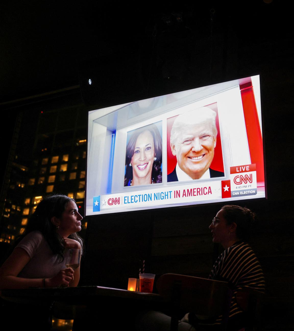 Menschen besuchen eine Wahlparty auf der 230 Fifth Rooftop Bar in New York City. Das Empire State Building ist im Hintergrund zu sehen.