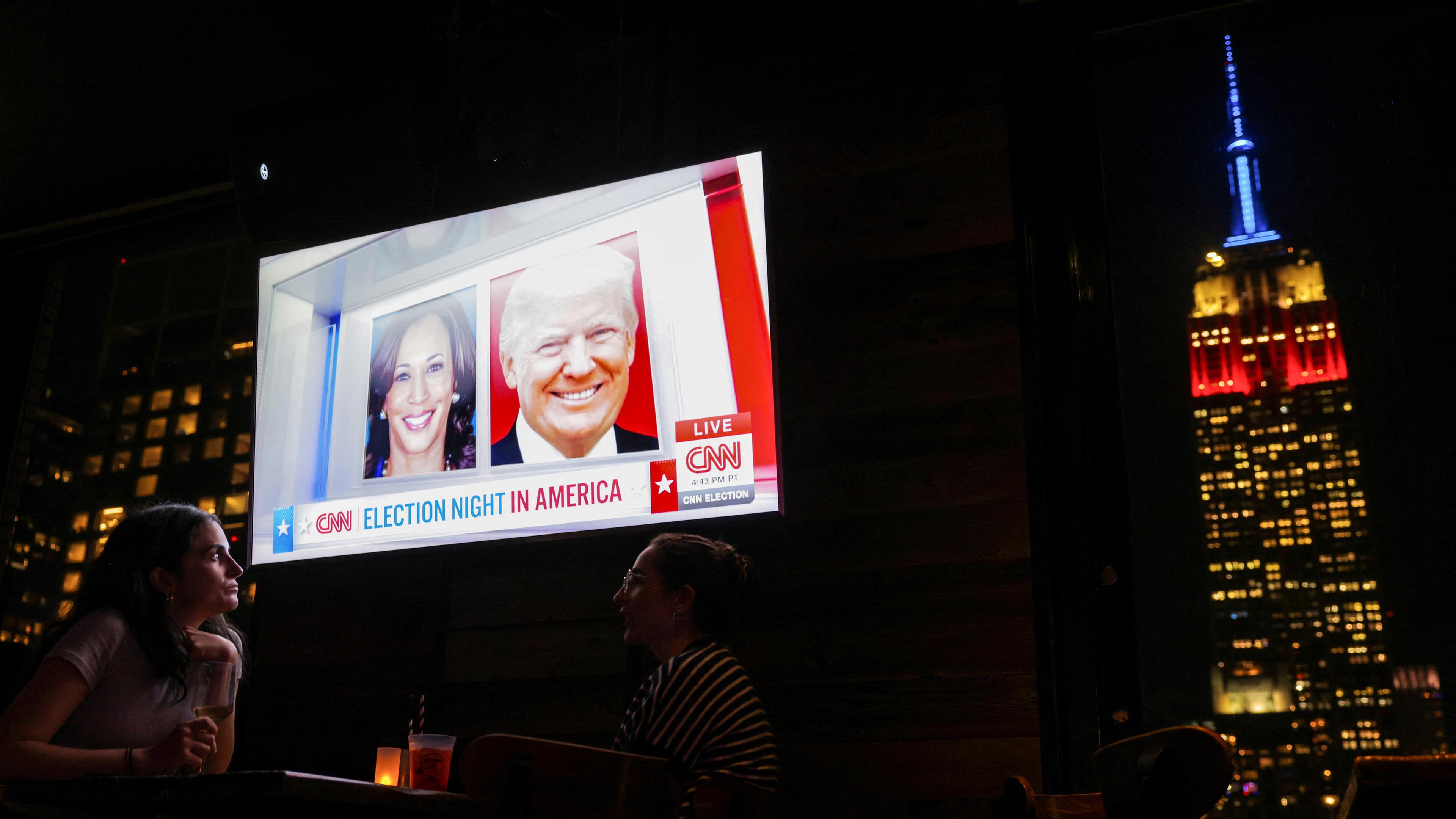 Menschen besuchen eine Wahlparty auf der 230 Fifth Rooftop Bar in New York City. Das Empire State Building ist im Hintergrund zu sehen.