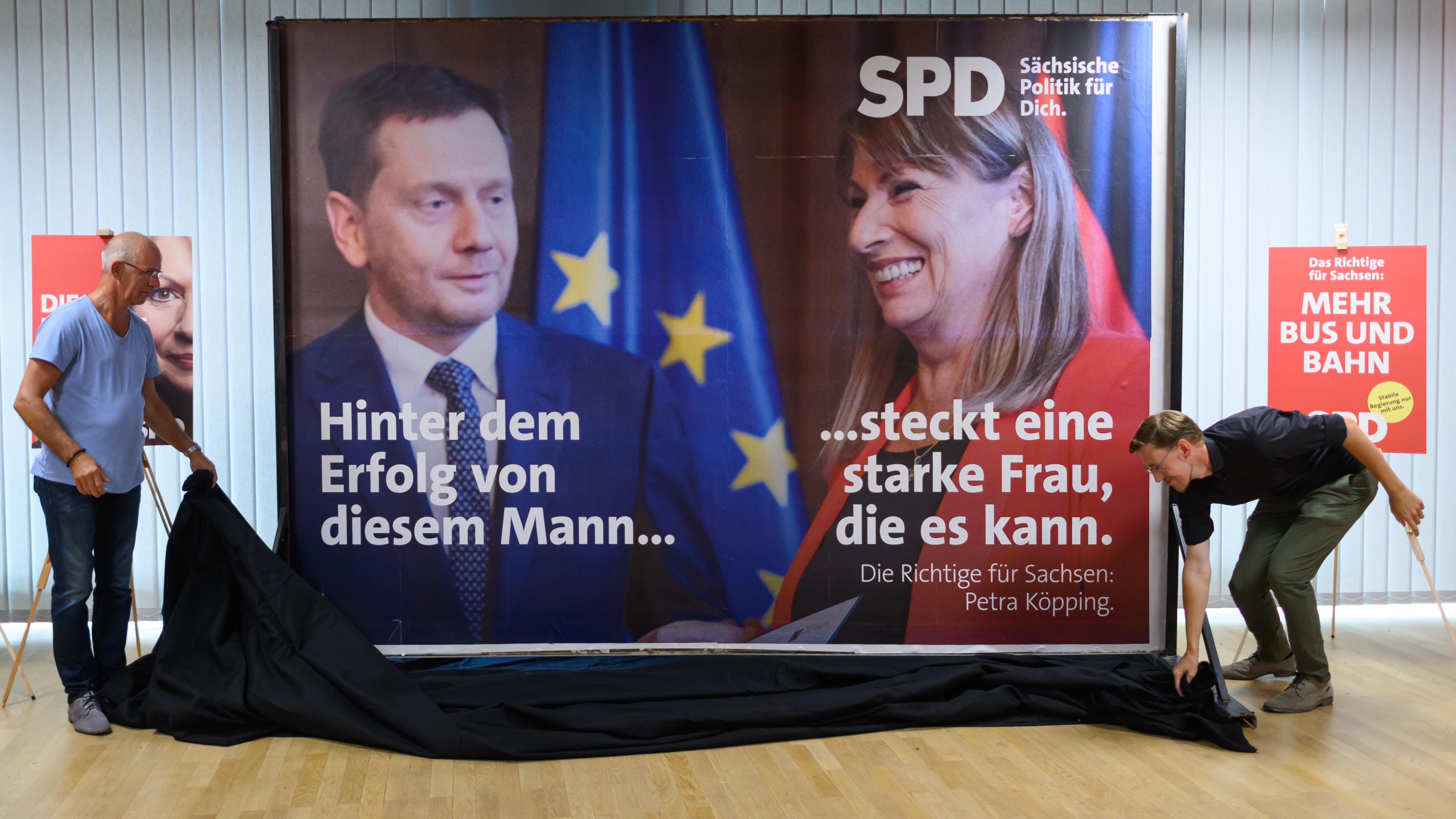 Mitarbeiter der SPD präsentieren bei Vorstellung der Kampagne für die Landtagswahl in Sachsen im Herbert-Wehner-Haus ein Plakat, das Michael Kretschmer (CDU, l), Ministerpräsident von Sachsen, und Petra Köpping (SPD), Sozialministerin von Sachsen und Spitzenkandidatin für die Landtagswahl, zeigt.