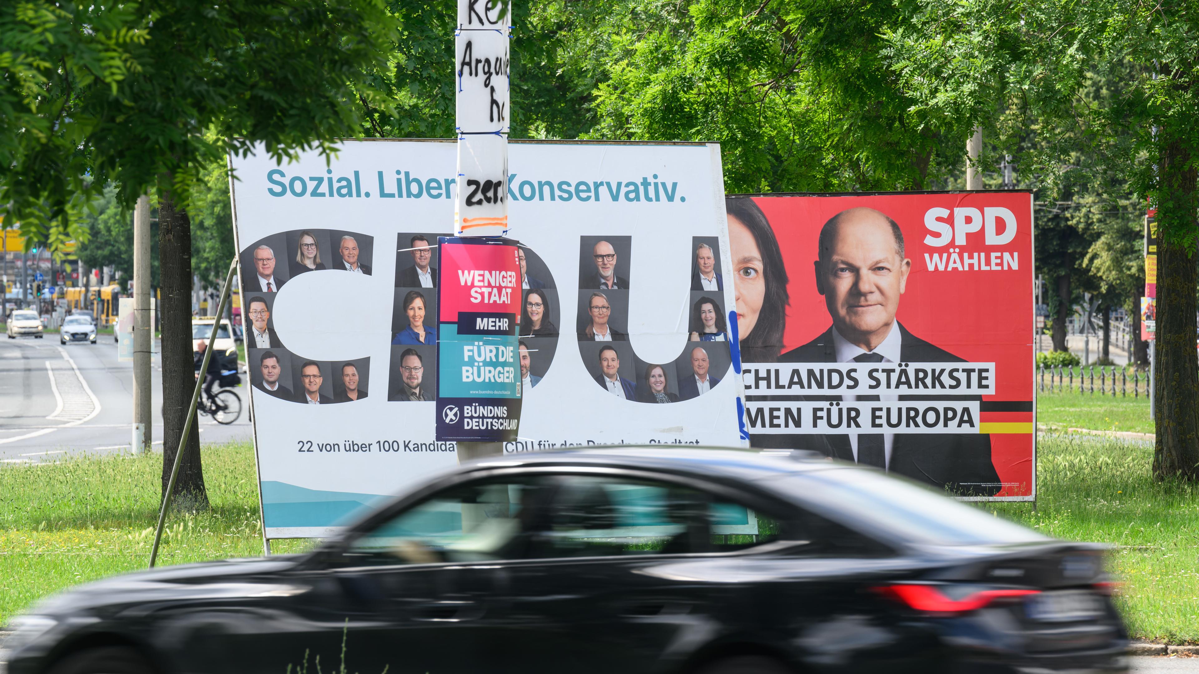 Wahlplakate verschiedener Parteien und Protestplakate hängen in der Innenstadt an Lichtmasten und sind auf Wänden aufgestellt.