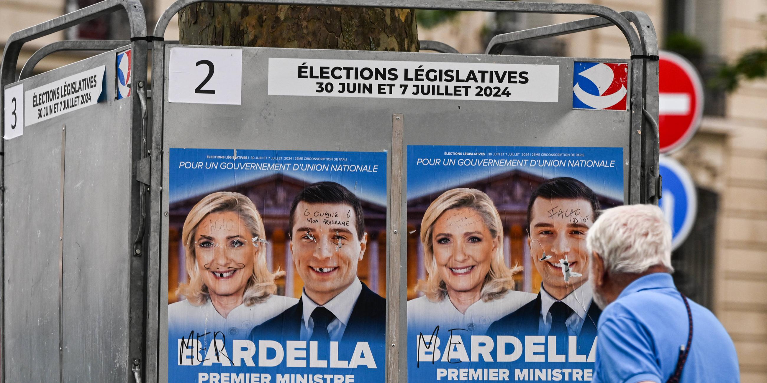 Ein Mann geht am 30. Juni an zerstörten französischen Parlamentswahlplakaten von Marine Le Pen, Präsidentin der Nationalen Rallye-Gruppe in der Nationalversammlung, und Jordan Bardella, Präsident der Nationalen Rallye, vorbei. 