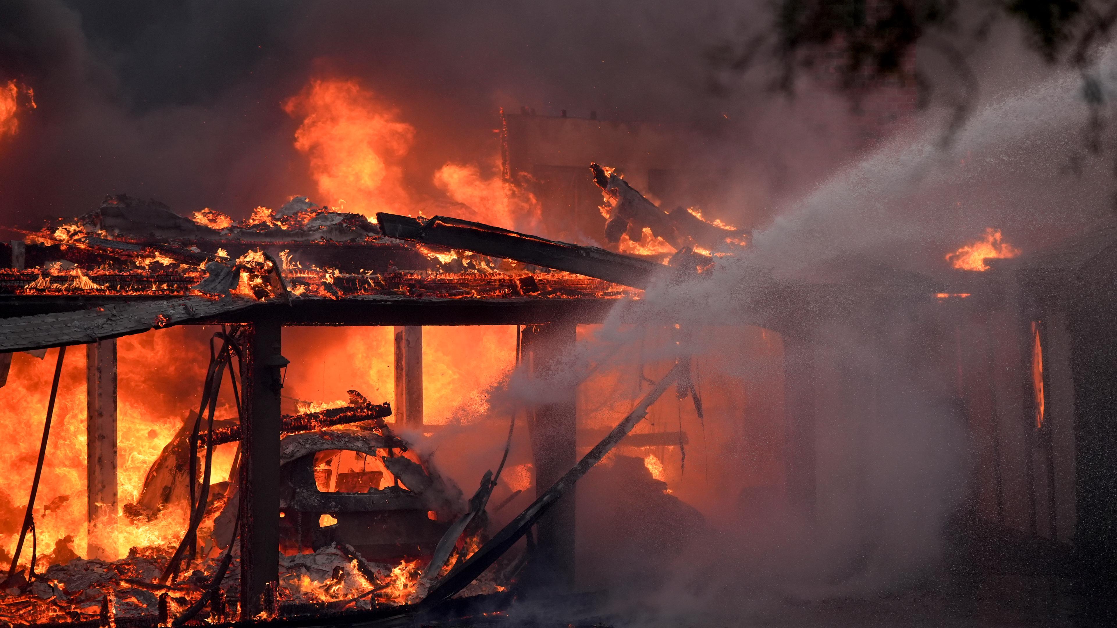 Feuerwehrleute löschen ein brennenden Haus während des "Mountain Fire".