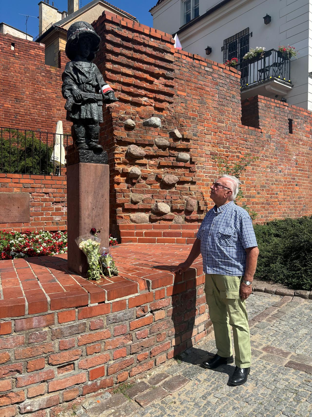 Widerstandskämpfer Janusz Maksymowicz steht vor dem Denkmal des Kleinen Aufständischen.