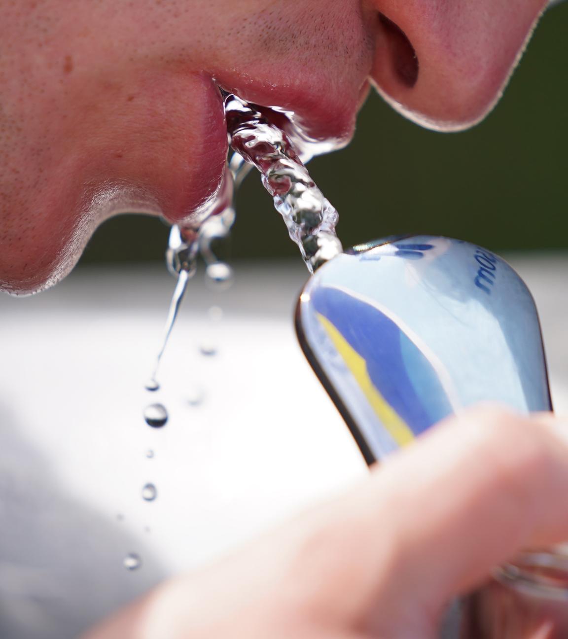 Mann trinkt an einem öffentlichen Wasserspender