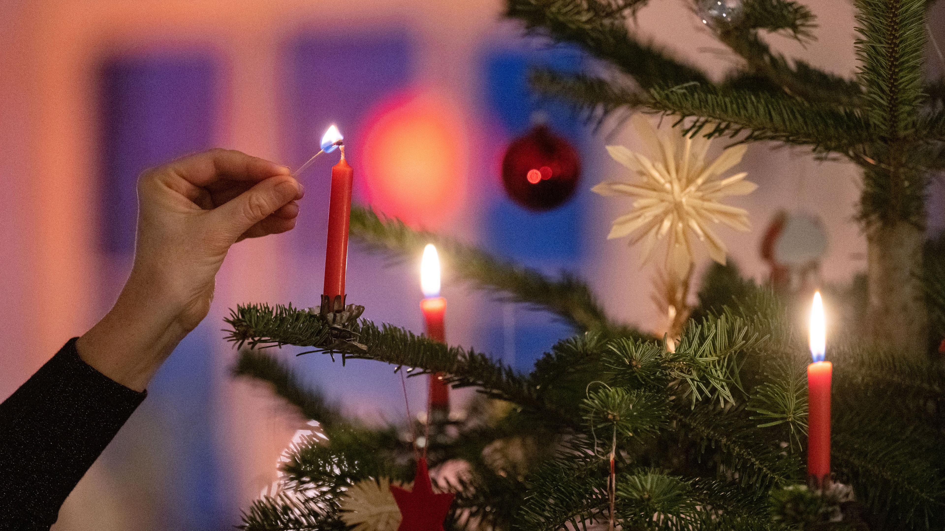 Kerzen an einem Weihnachtsbaum werden angezündet.