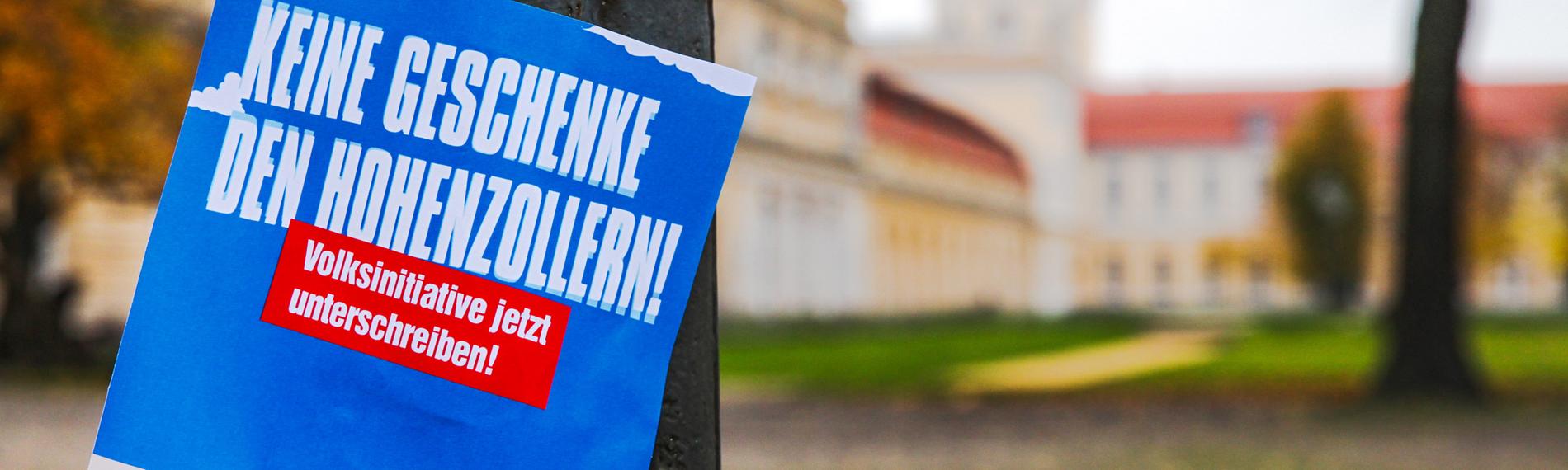 Plakat "Keine Geschenke den Hohenzollern" vor Schloss Charlottenburg in Berlin