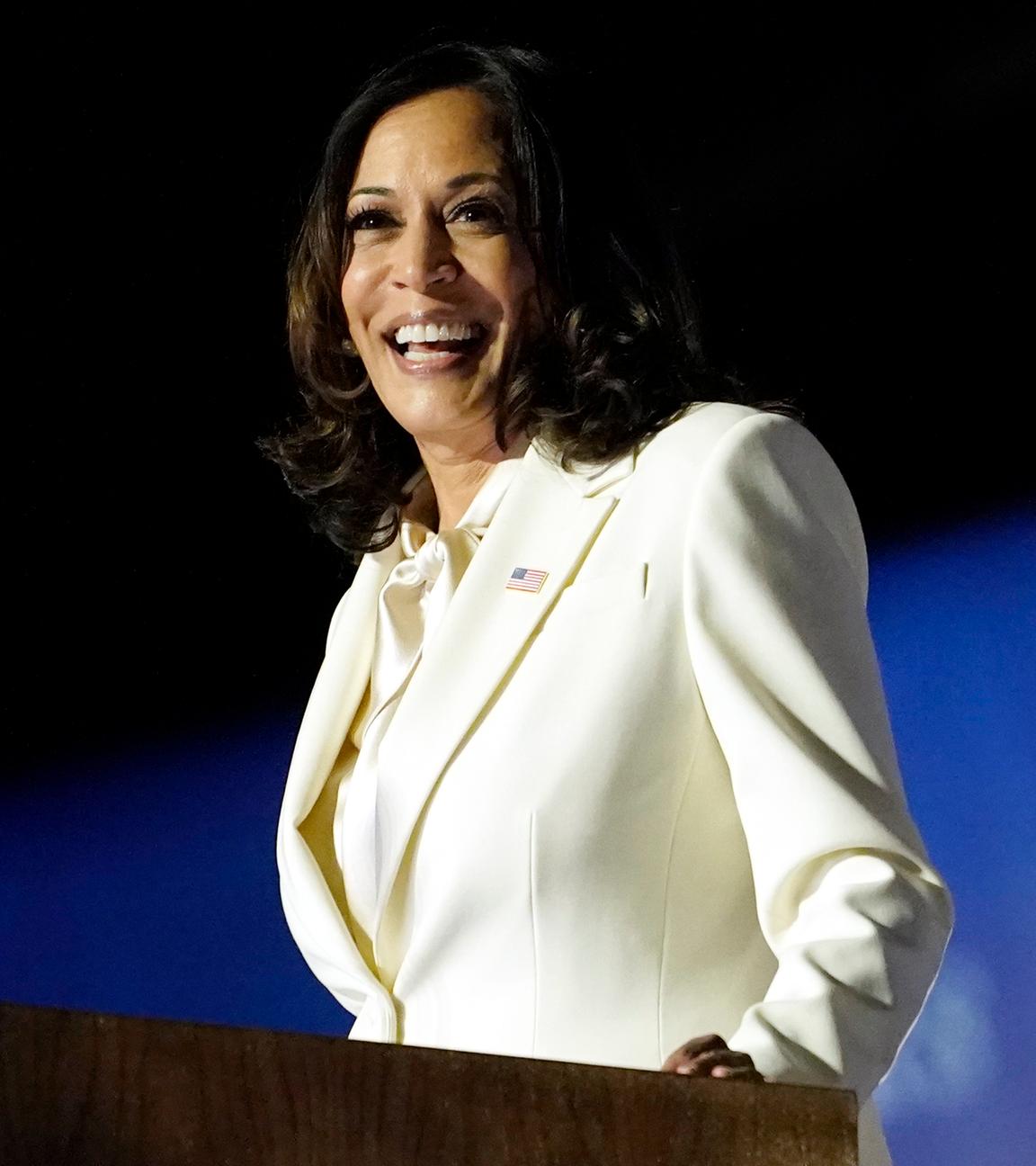 Kamala Harris steht an einem Rednerpult. Sie lächelt. 