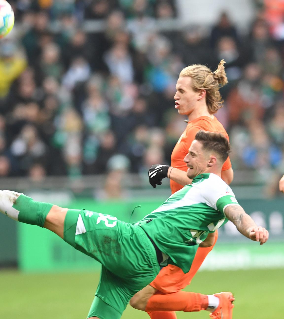 Werders Marco Friedl (v) kämpft gegen Wolfsburgs Patrick Wimmer um den Ball. Im Hintergrund Werders Anthony Jung (r).