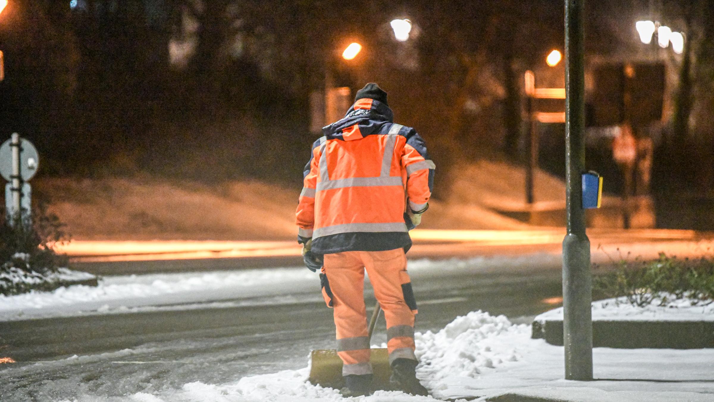 Baden-Württemberg, Aalen: Ein Mitarbeiter der Stadt Aalen schiebt Schnee von einem Fußgängerüberweg weg.