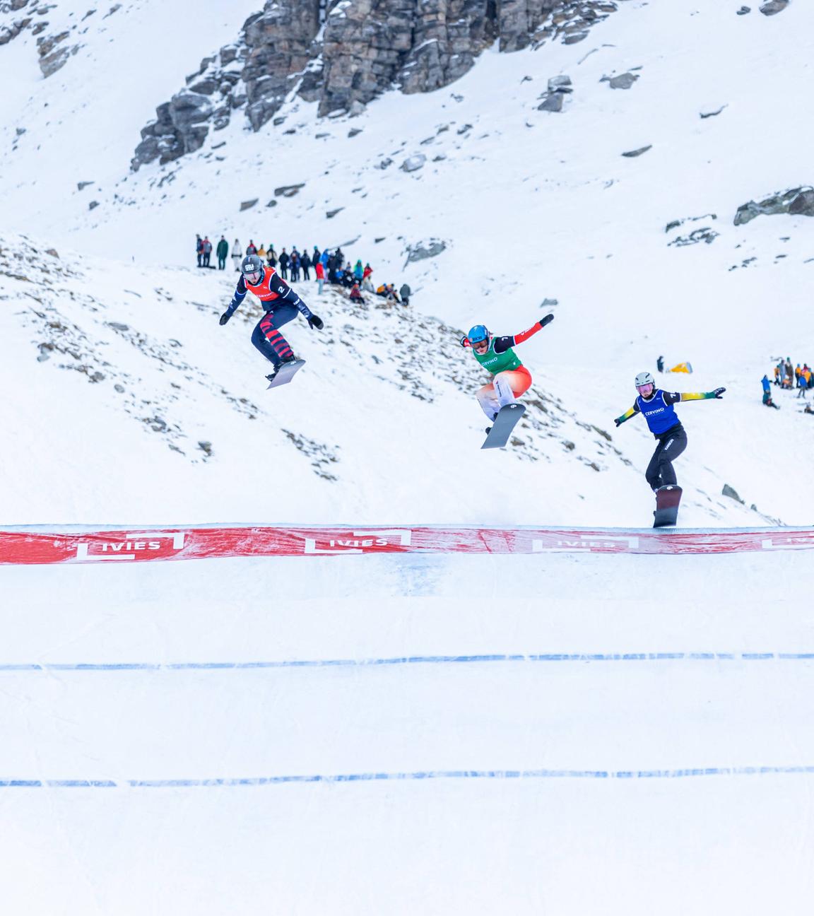 Die Snowboarder*innen springen über einen Hügel während dem Viertelfinale in Cervinia.