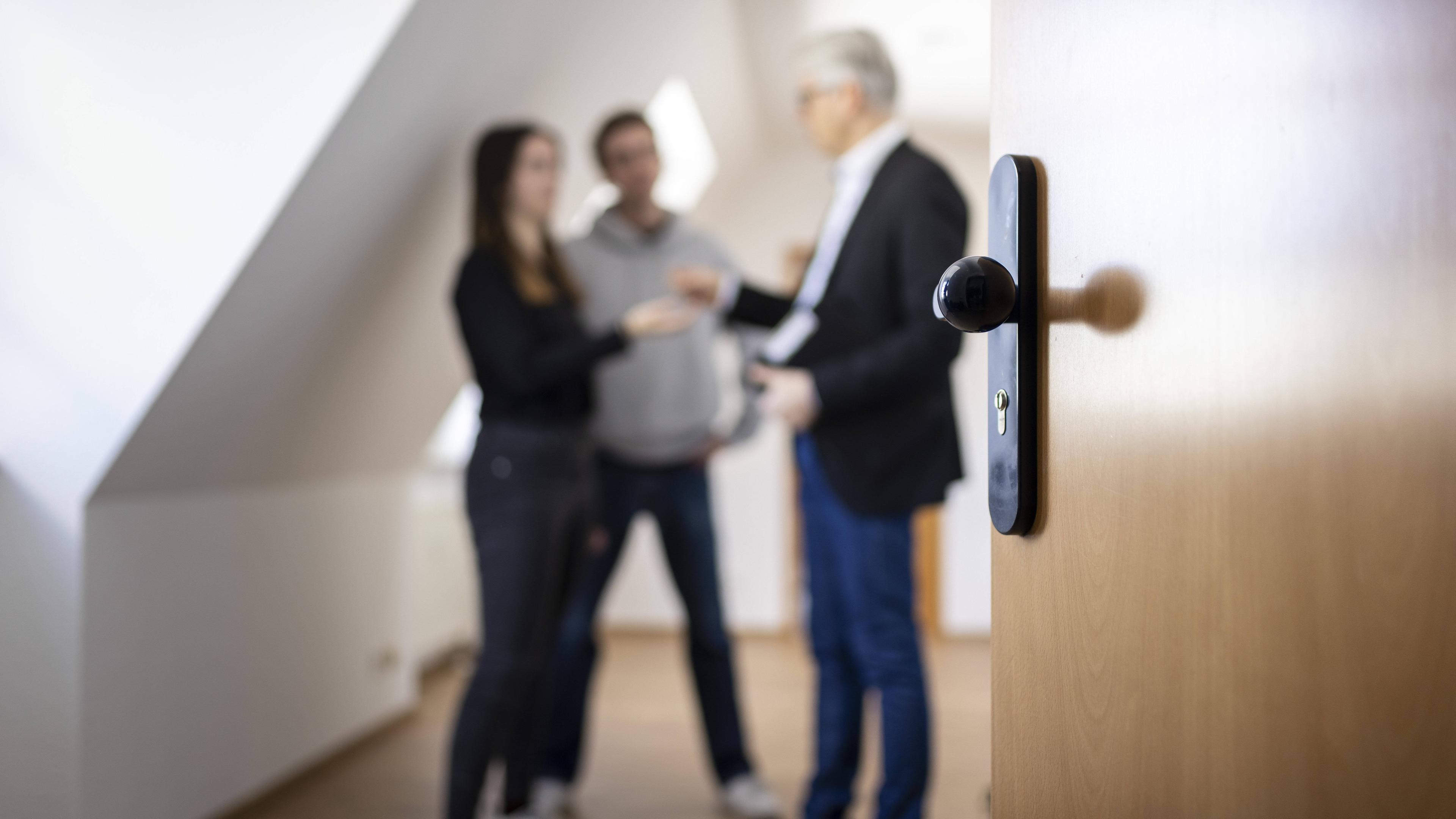 Juges Paar bei einer Wohnungsbesichtigung steht zusammen mit dem Vermieter in der offenen Tür.