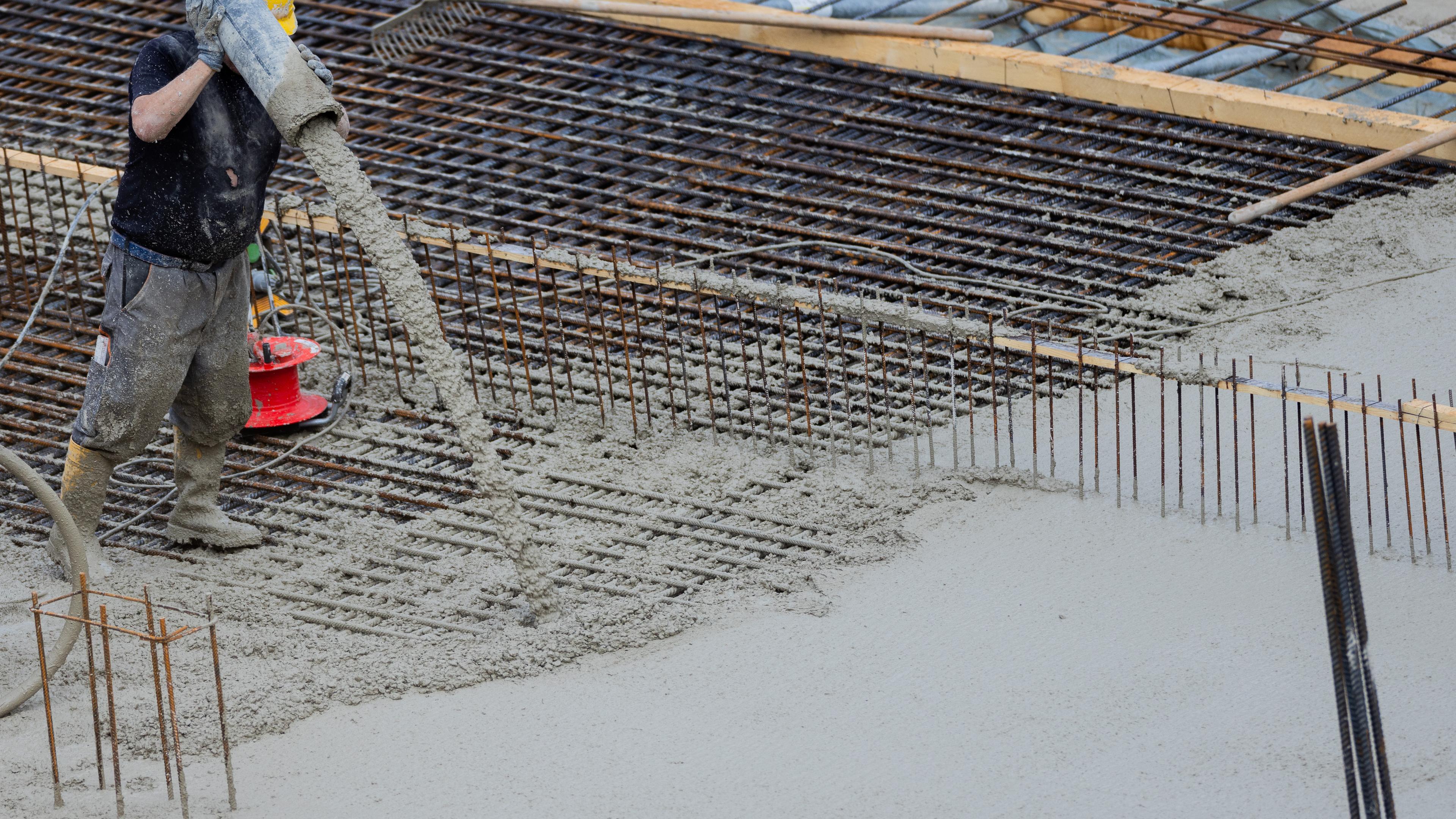 Nordrhein-Westfalen, Köln: Flüssiger Beton für eine Bodenplatte eines Rohbaus für Eigentumswohnungen im Stadtteil Ehrenfeld wird in eine Stahlkonstruktion gefüllt.