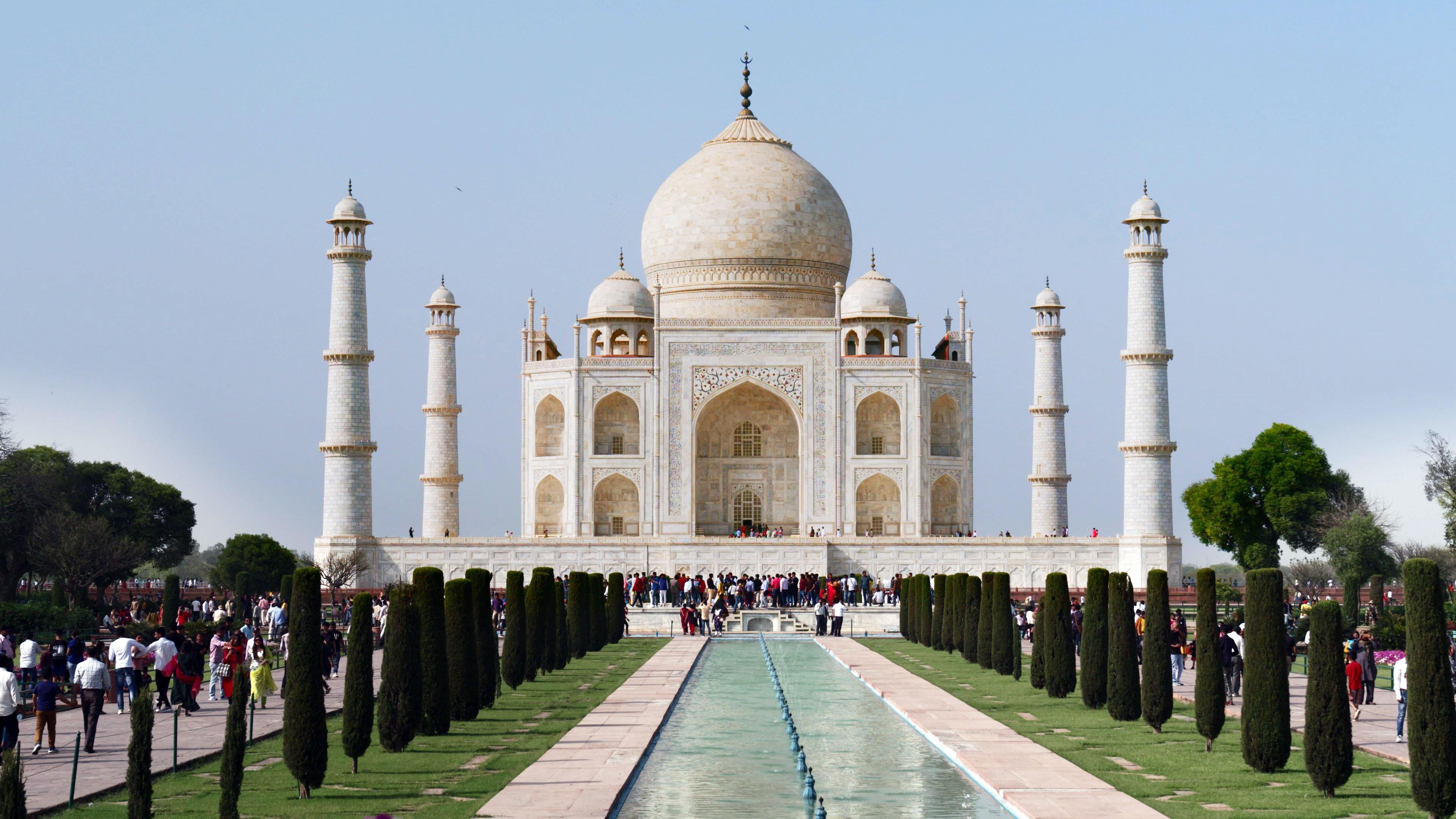 Ein mit Bäumen umrahmtes Wasserspiel führt zu einem großen erhöhten Platz, auf dem ein weißer Kuppelbau steht. Um den Bau herum stehen vier Minarette.