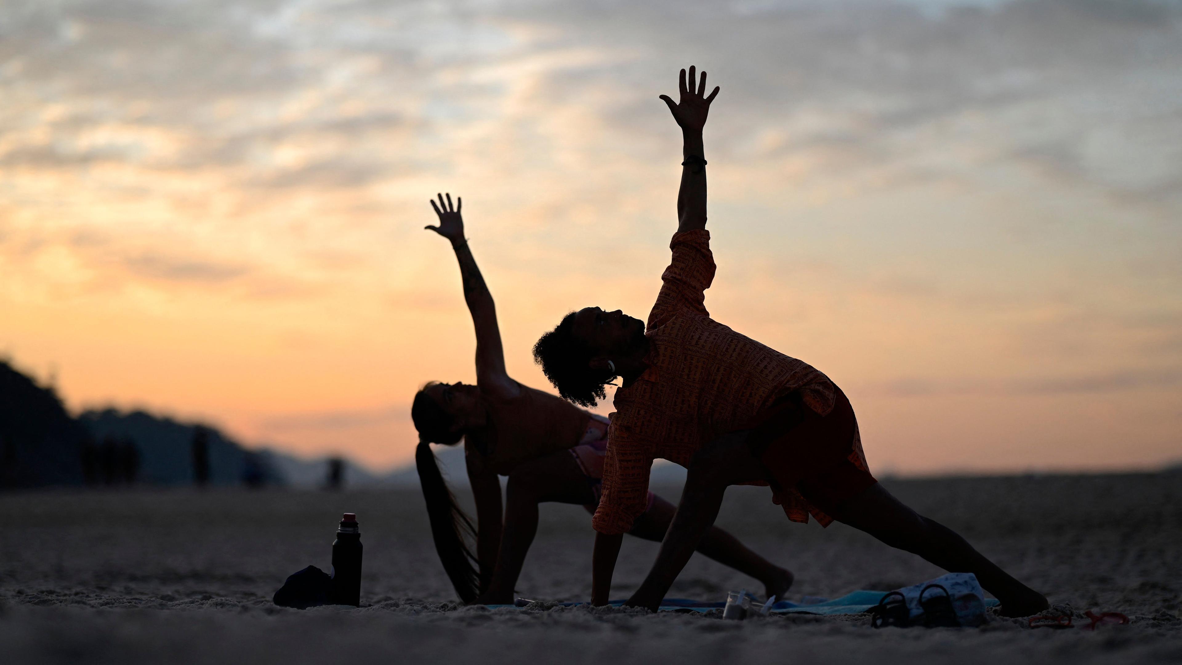 Menschen nehmen am 22. Juni 2024 an der Veranstaltung „Yoga ao Sol Nascer“ (Yoga bei Sonnenaufgang) am Copacabana-Strand in Rio de Janeiro, Brasilien, teil. 