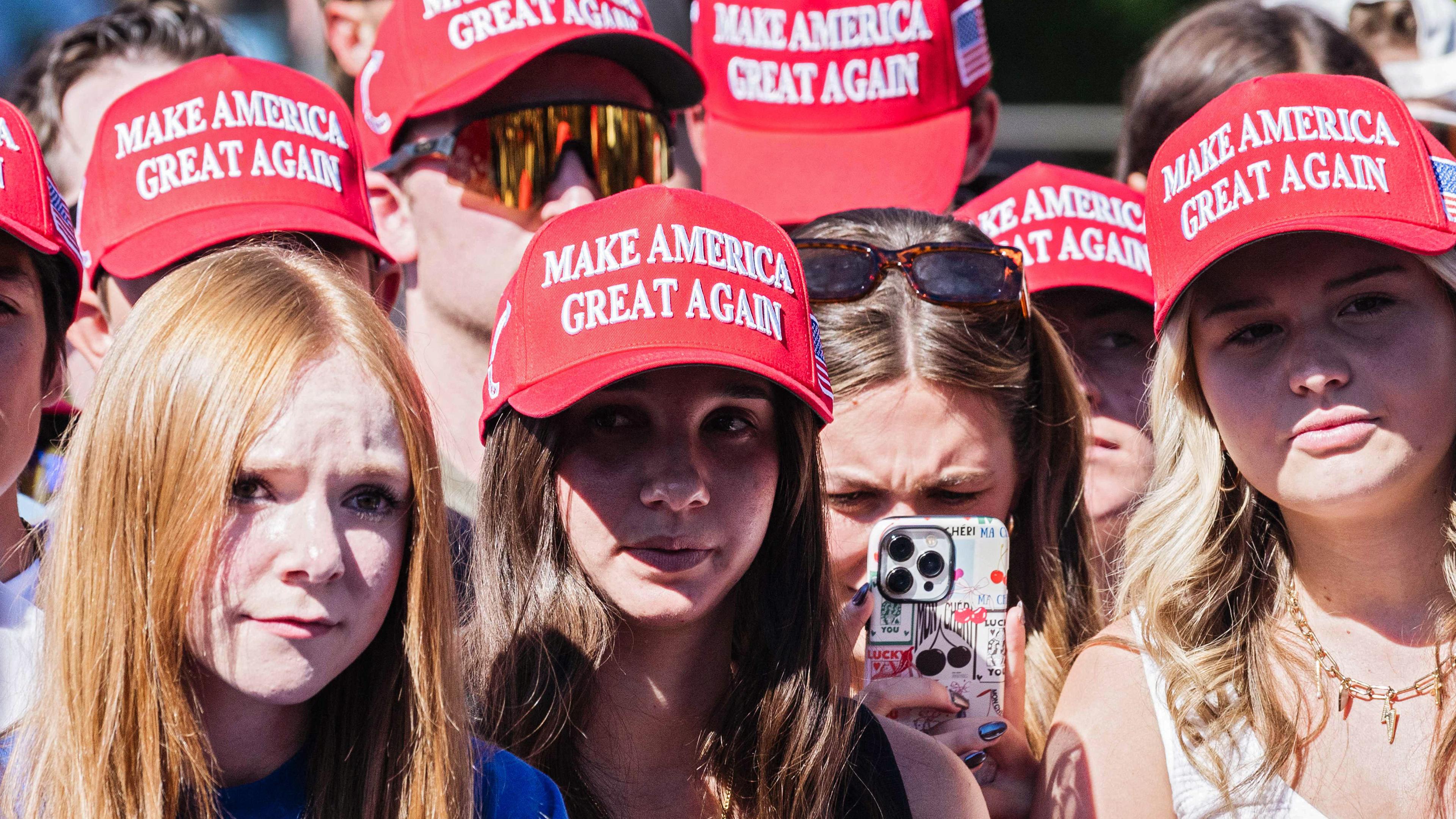 Eine Gruppe junger Menschen trägt rote Kappen mit der Aufschrift Make Amerika Great Again.