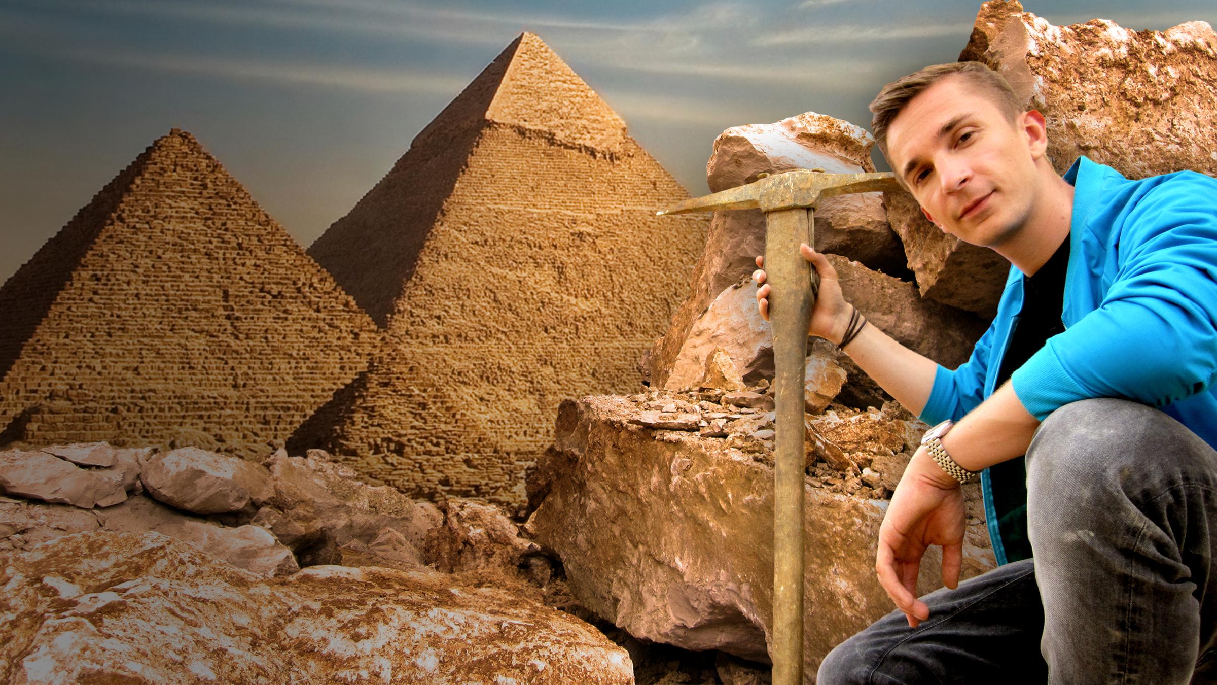 Eric sitzt mit einer Hacke vor eine Pyramide und einem Steinbruch