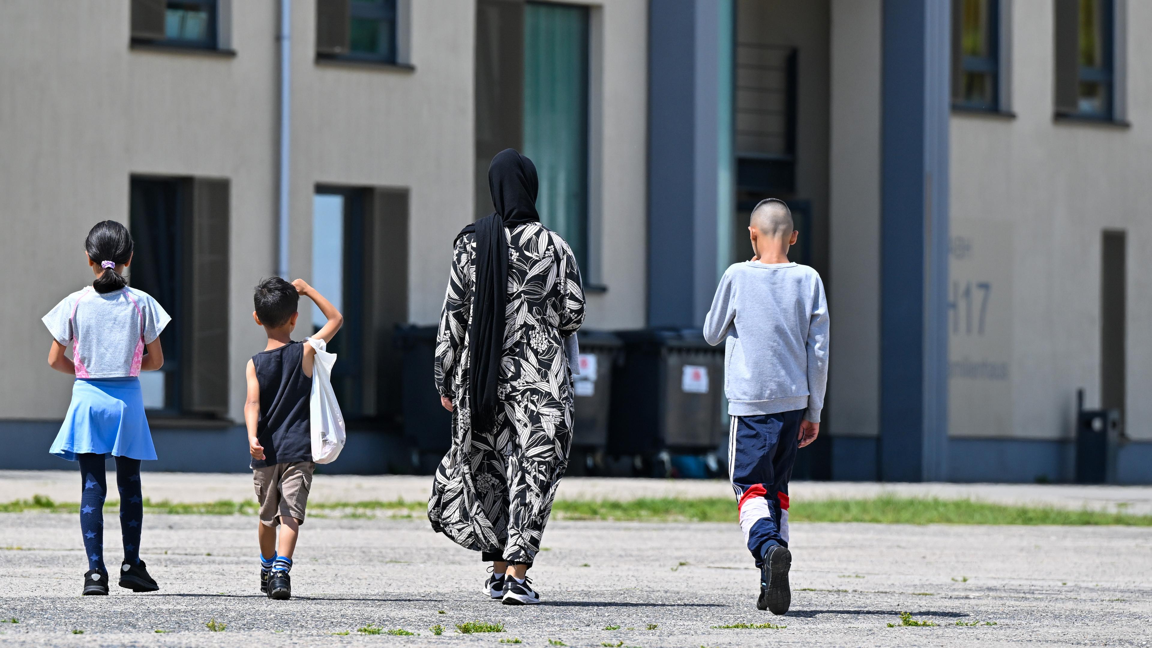 Brandenburg, Eisenhüttenstadt: Eine Migrantin und ihre drei Kinder gehen über das Gelände der Zentralen Erstaufnahmeeinrichtung für Asylbewerber (ZABH) des Landes Brandenburg.