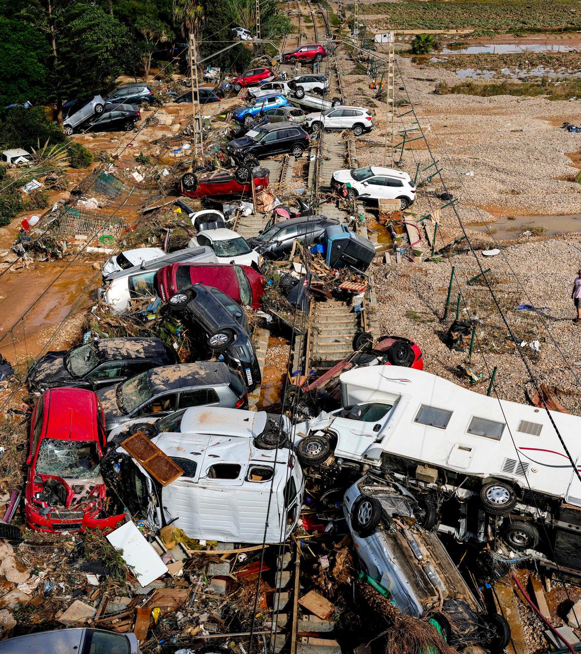 Ein Mann steht neben Autos, die nach dem Unwetter übereinander liegen. 