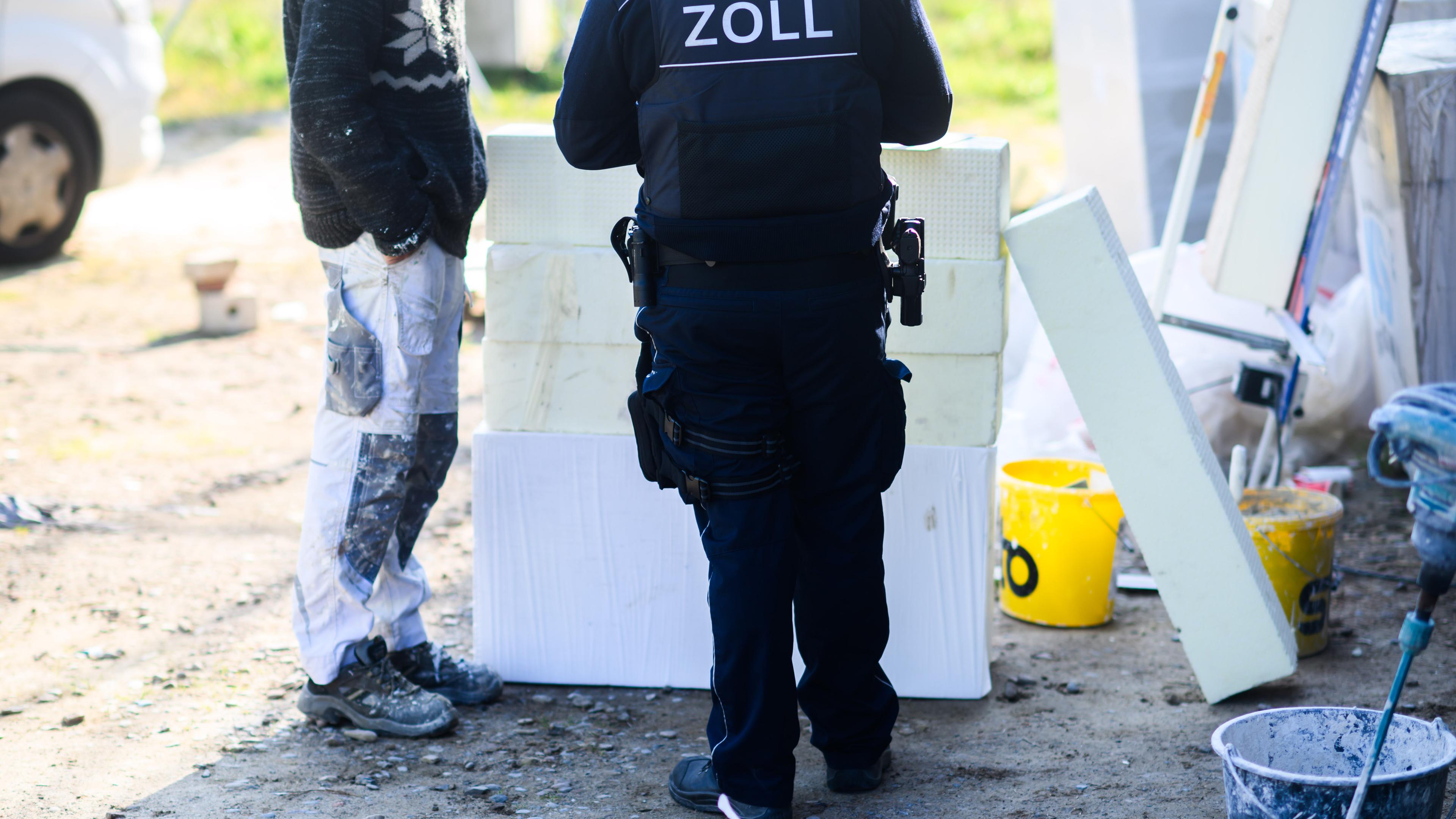 Niedersachsen, Garbsen: Ein Zollbeamter (r.) steht mit einem Bauarbeiter bei einer Kontrolle von Schwarzarbeit in einem Neubaugebiet in der Region Hannover. 